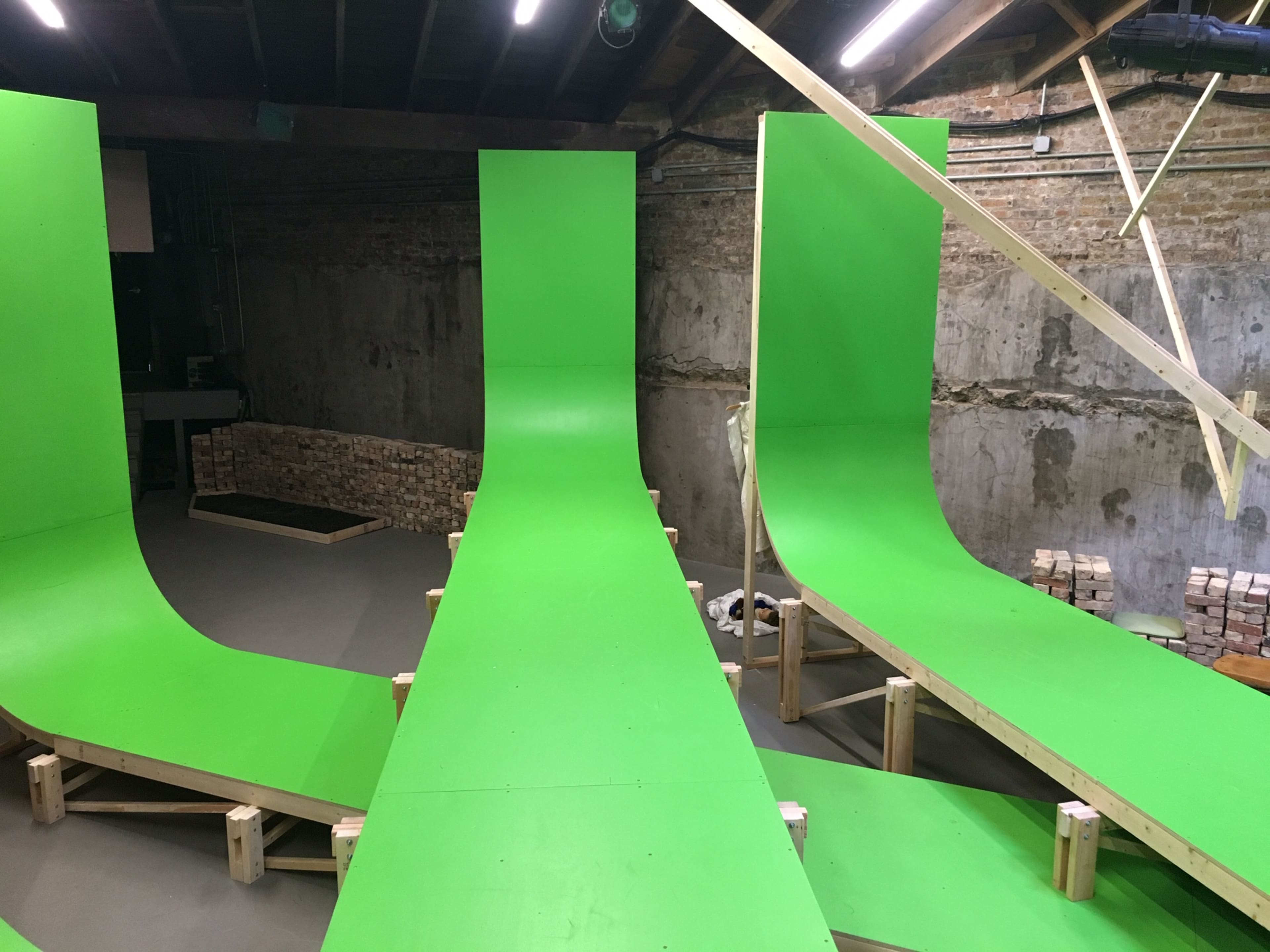 A series of green ramps set up in a warehouse, with wooden supports beneath them.