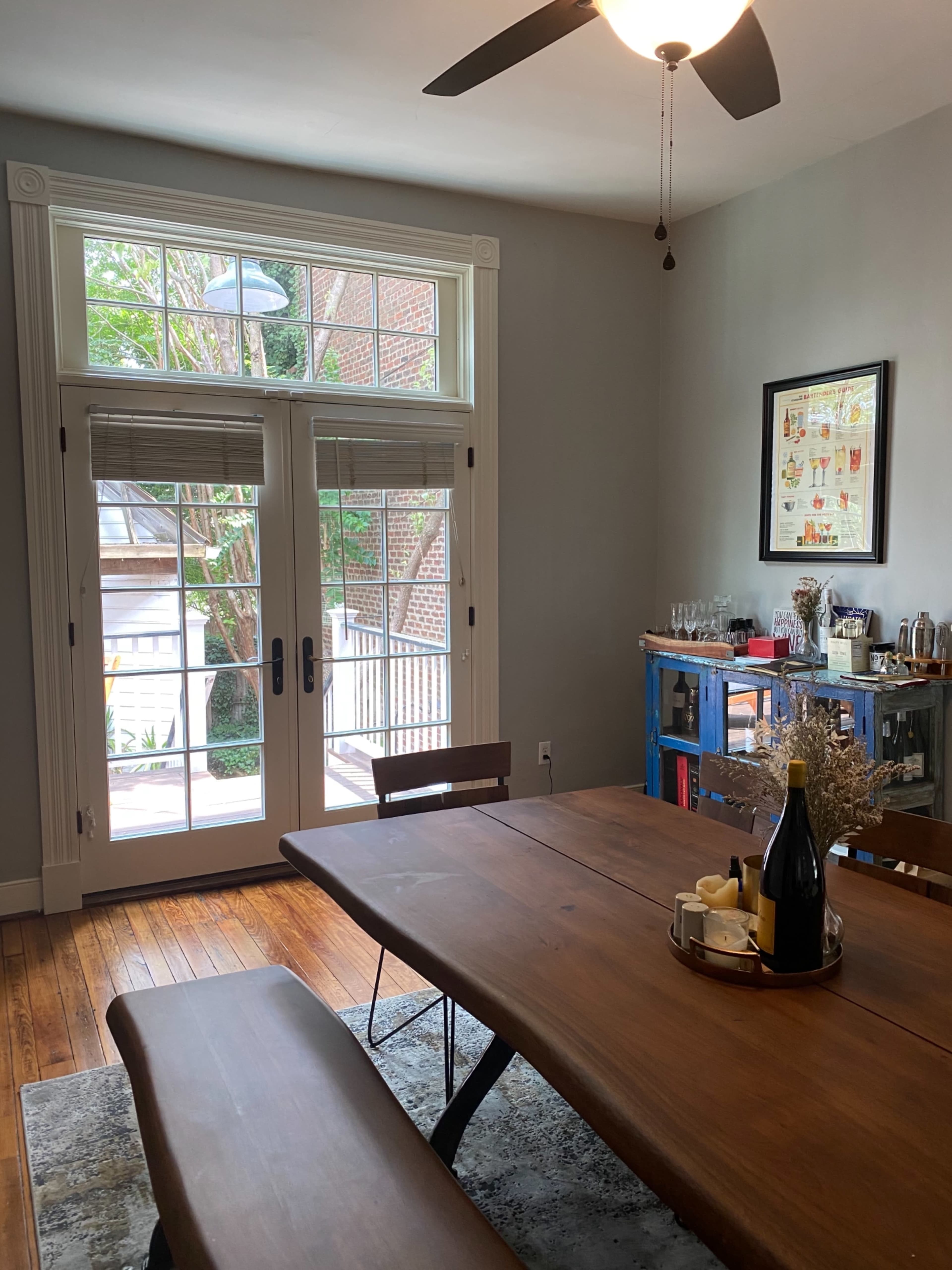 A dining room featuring a wooden table and bench, with large glass doors leading to an outdoor area.