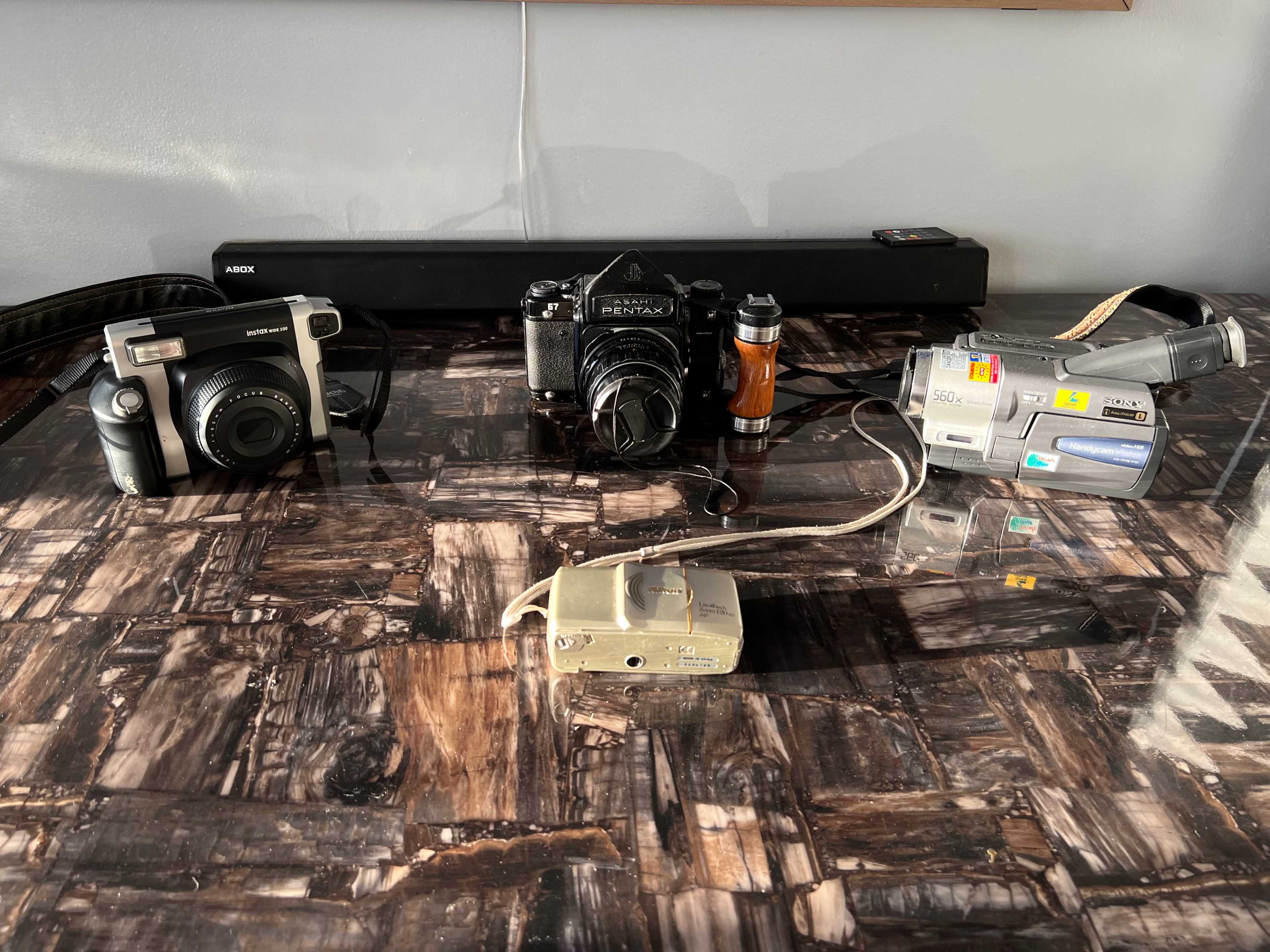 Three cameras and a video camera arranged on a textured surface.