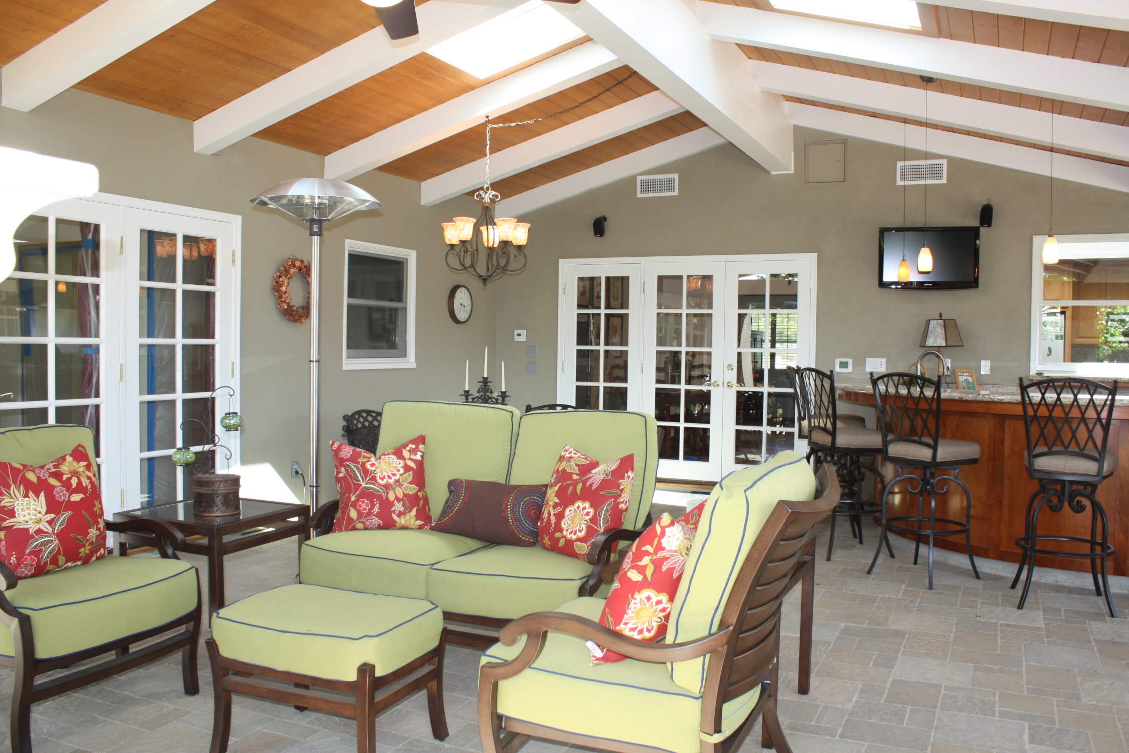 A sunlit indoor seating area with green upholstered furniture and a bar in the background.