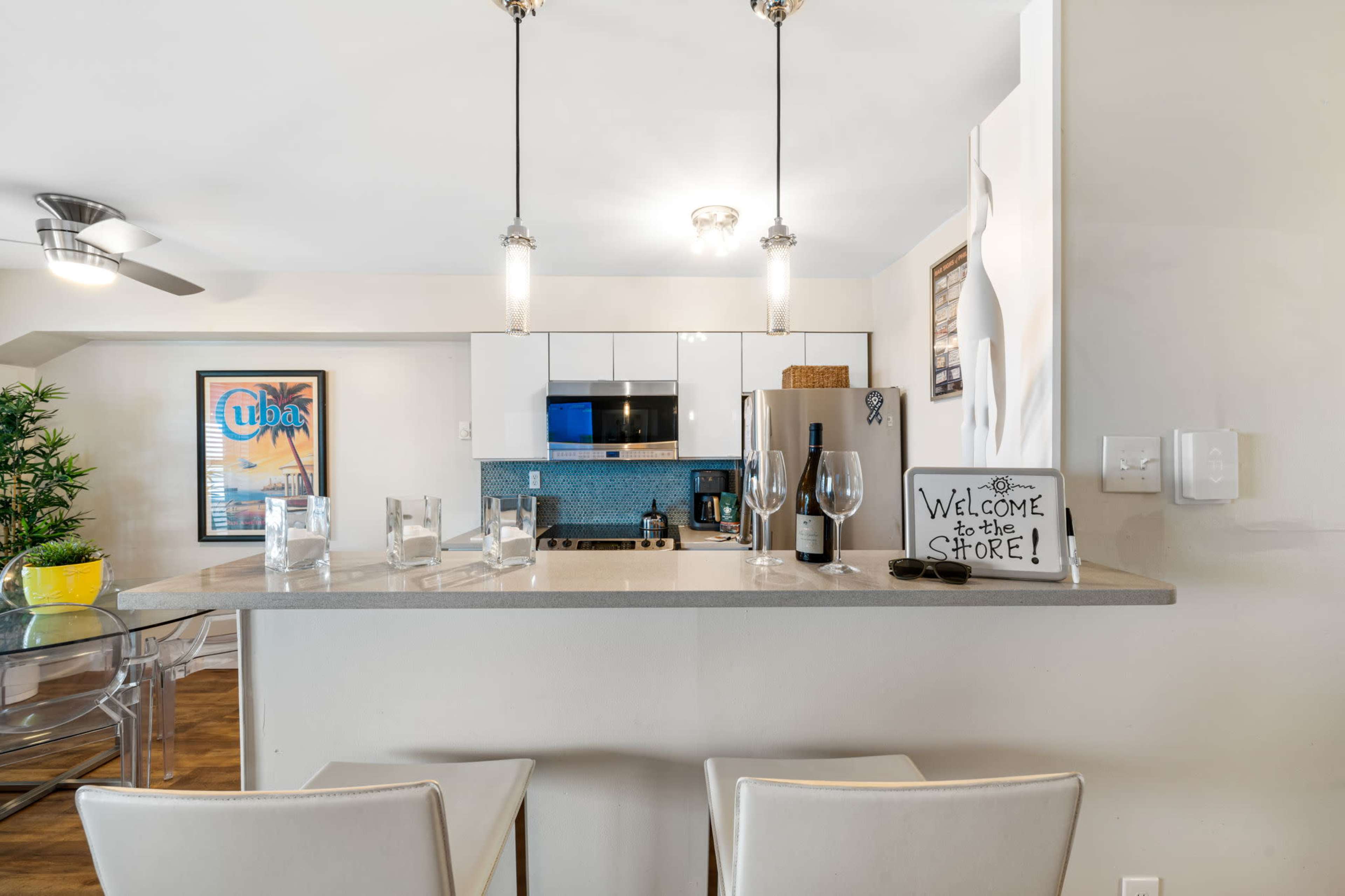 A modern kitchen with a bar countertop, featuring appliances, a small dining area, and decorative elements.
