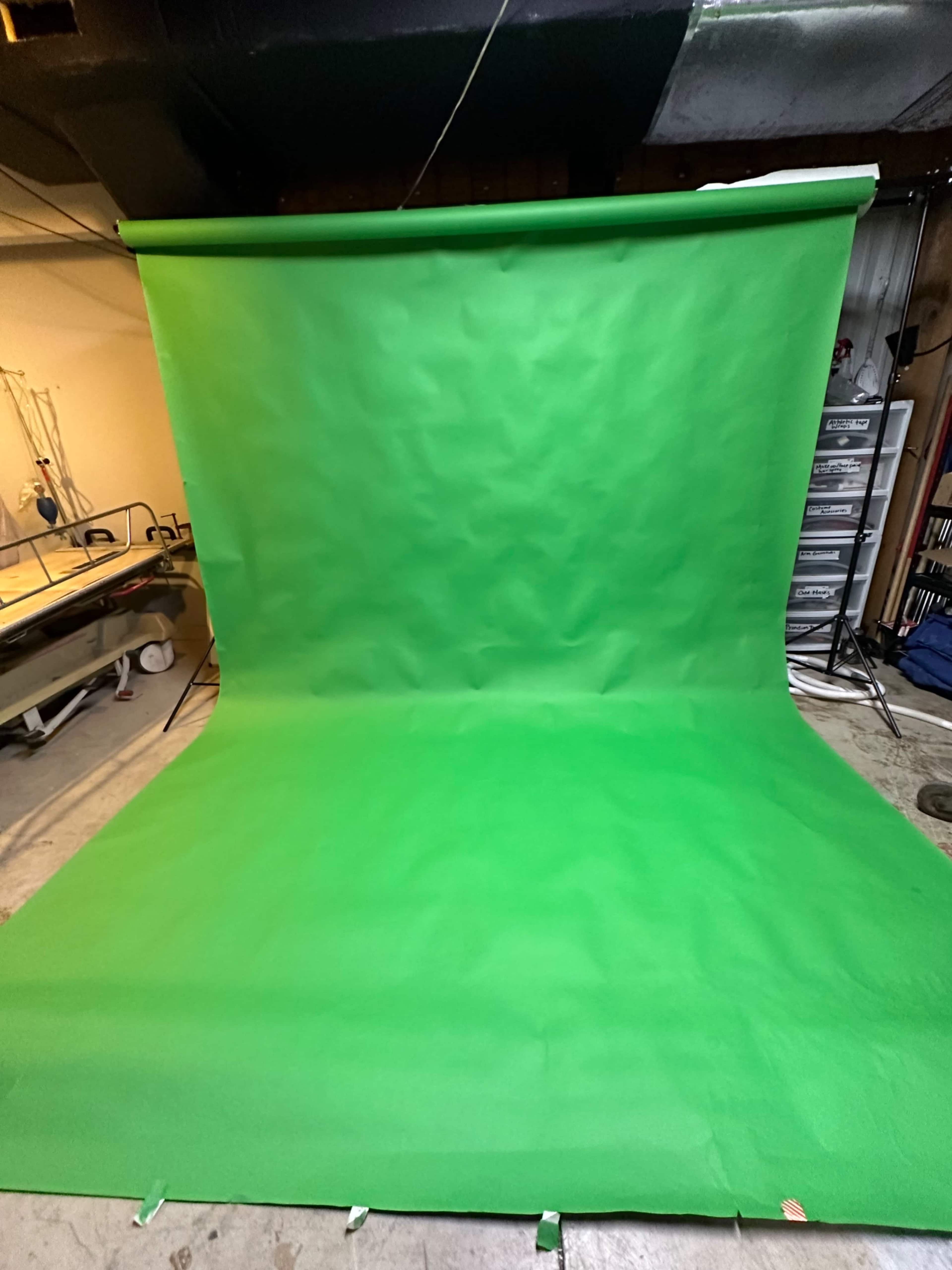A large green backdrop set up in a studio environment, with a smooth surface and a slight fold at the bottom.