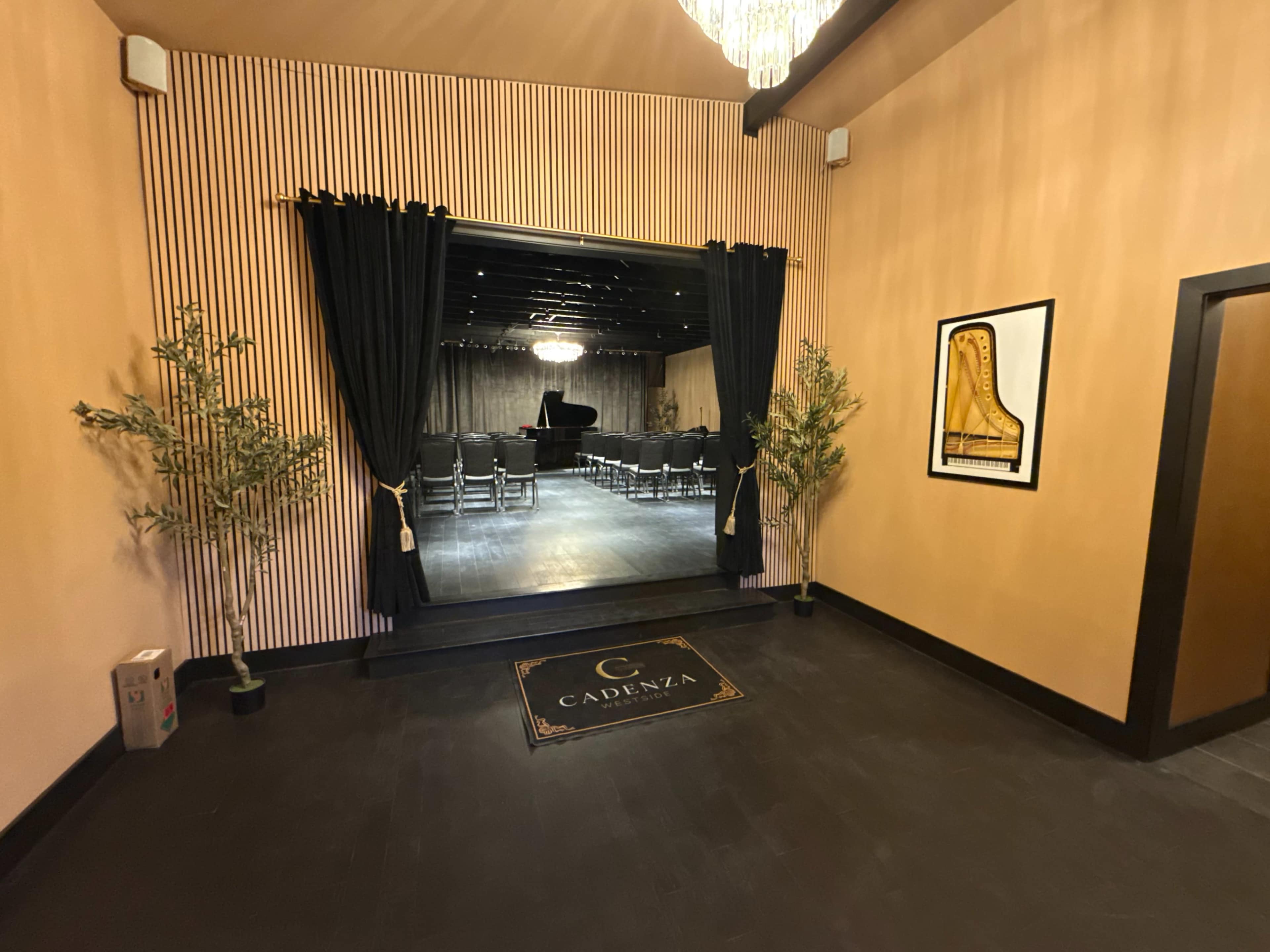 A well-decorated entrance leads to a rehearsal space featuring a grand piano and chairs arranged for an audience.