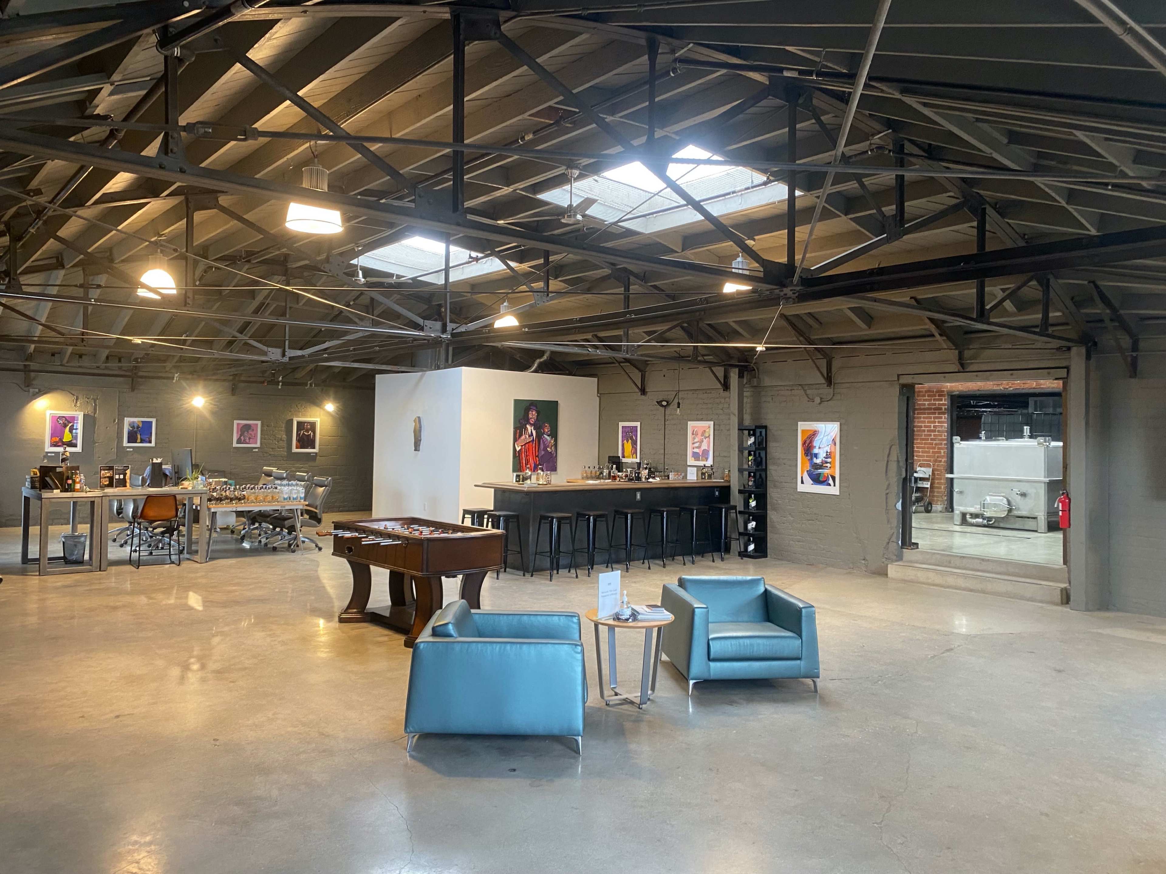 A spacious industrial-style interior with a game table, bar area, and seating arrangements.
