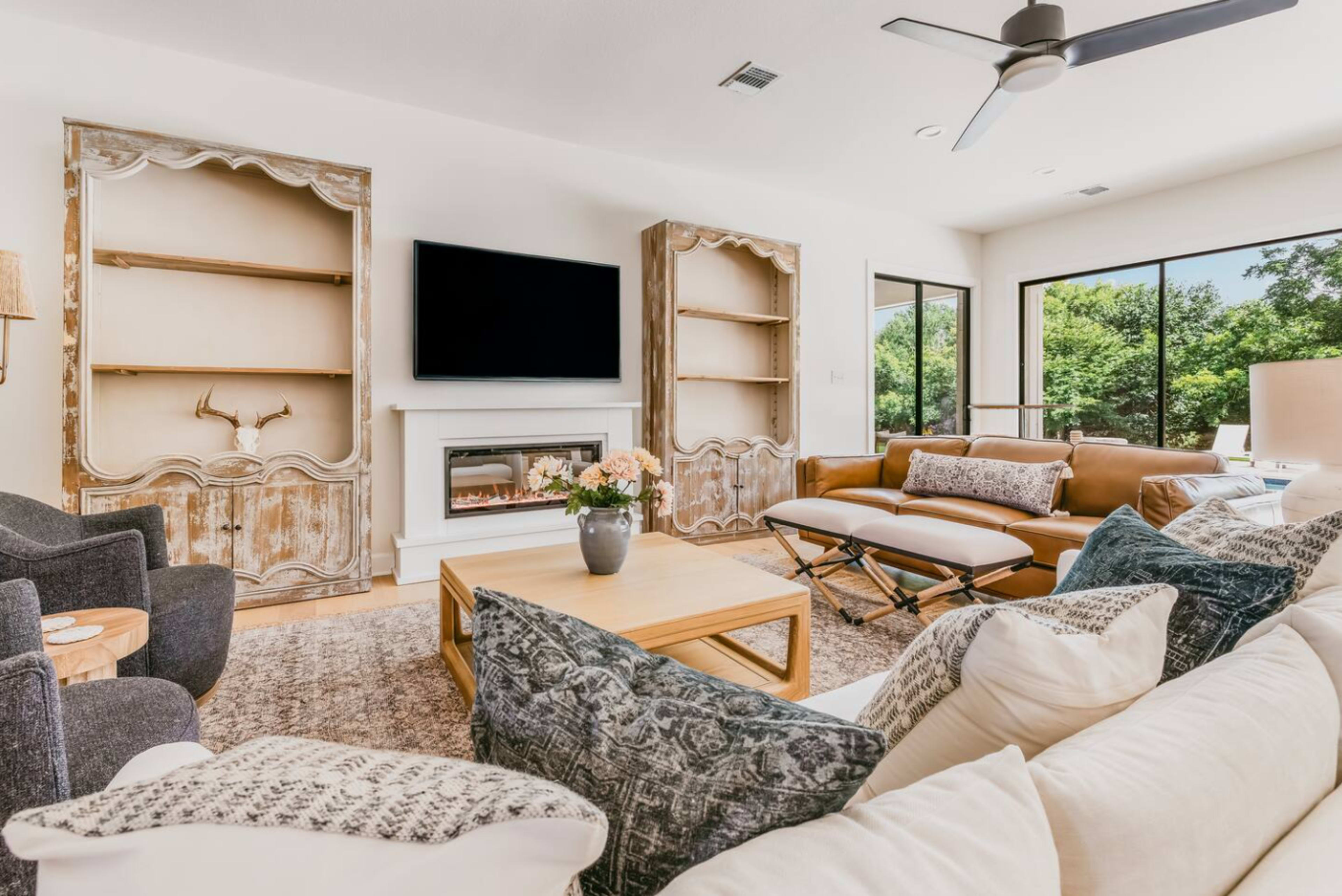 The living room features a combination of light-colored walls, a modern television mounted above a fireplace, and a mix of rustic and contemporary furnishings.