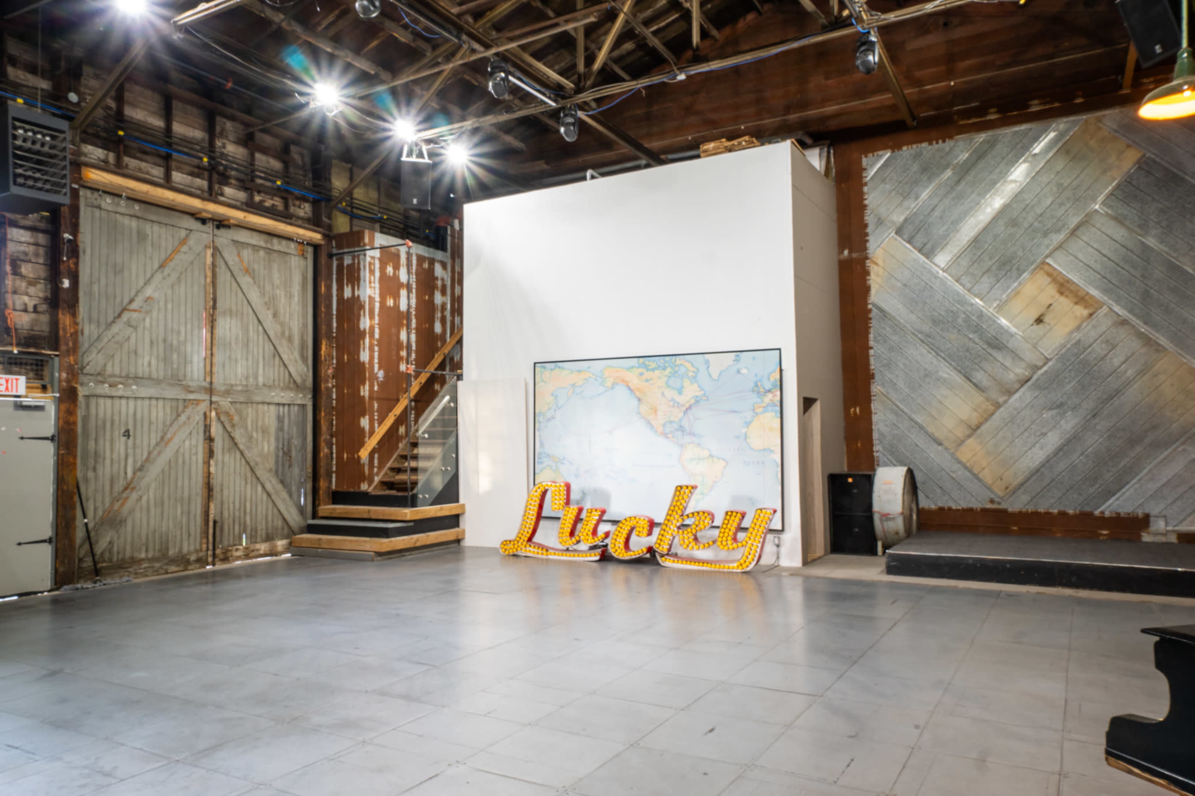 The image shows a spacious indoor area with a large map and a bright "Lucky" sign on the floor, featuring wooden walls and a lofted section in the background.