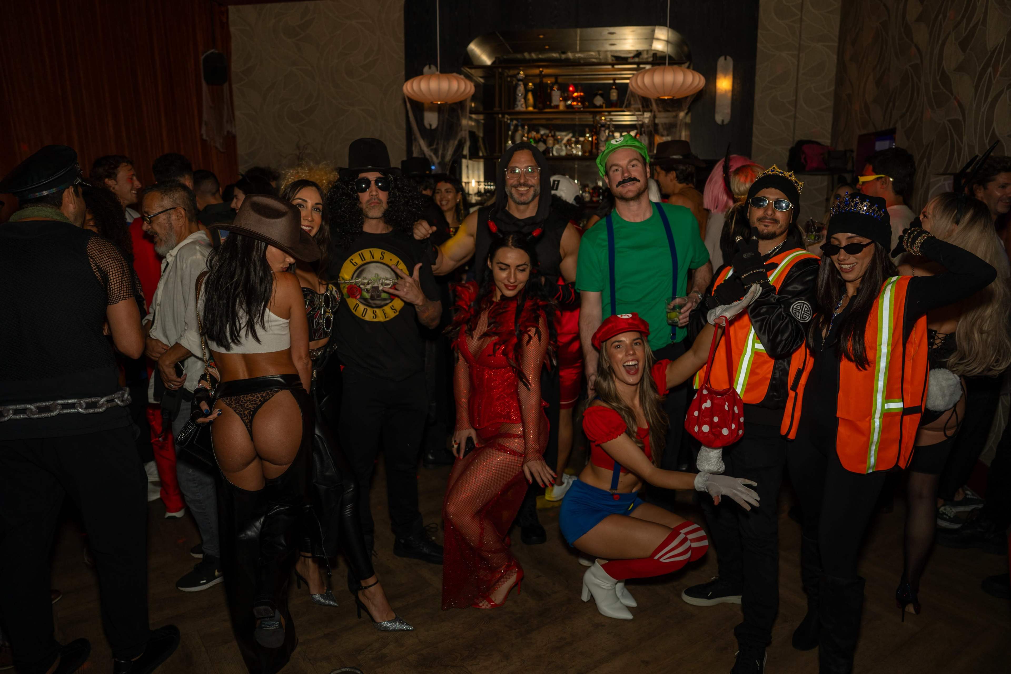 A diverse group of people dressed in various costumes enjoys a lively party atmosphere.