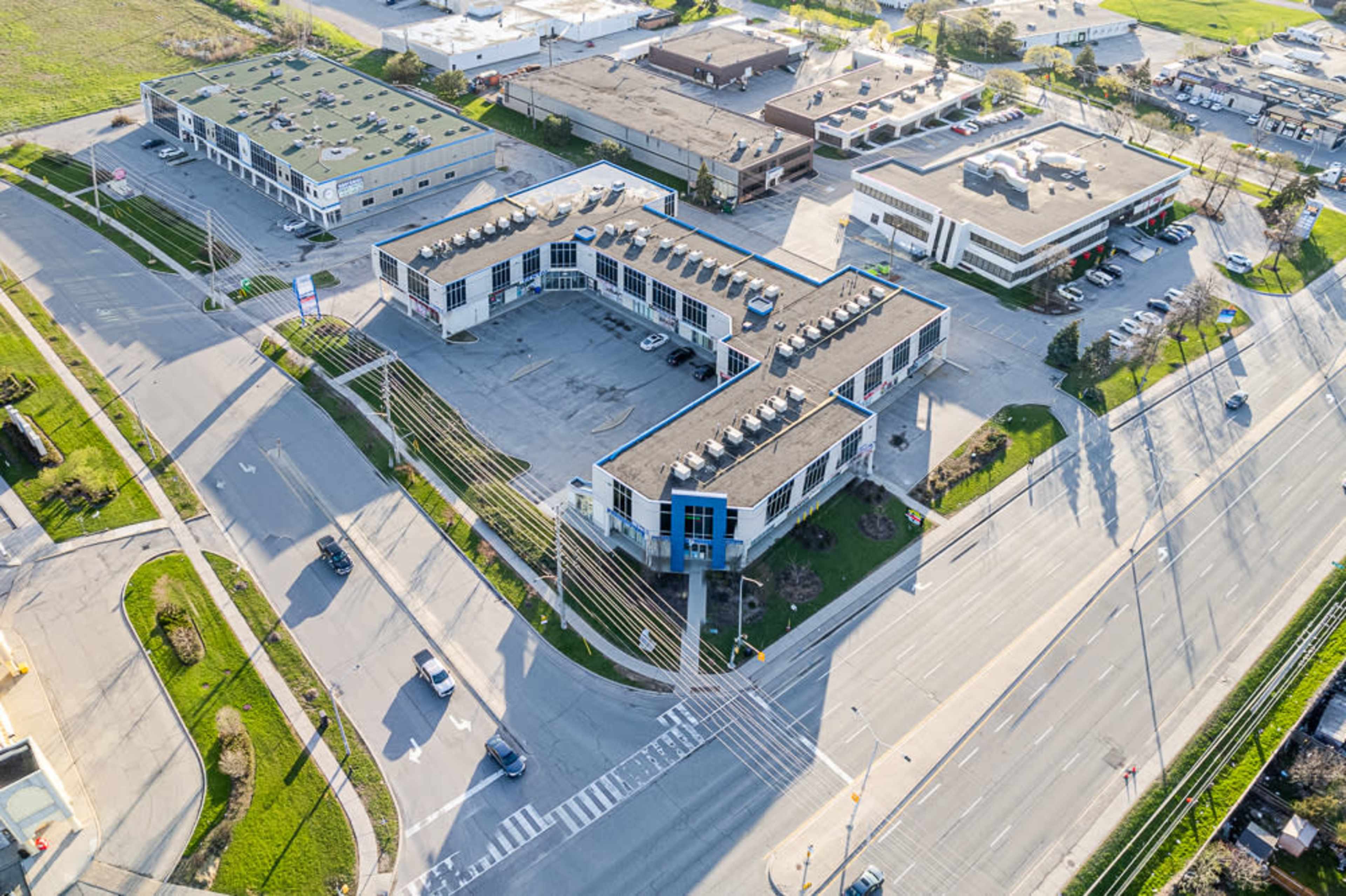 An aerial view shows a commercial building surrounded by roads, parking lots, and green spaces.