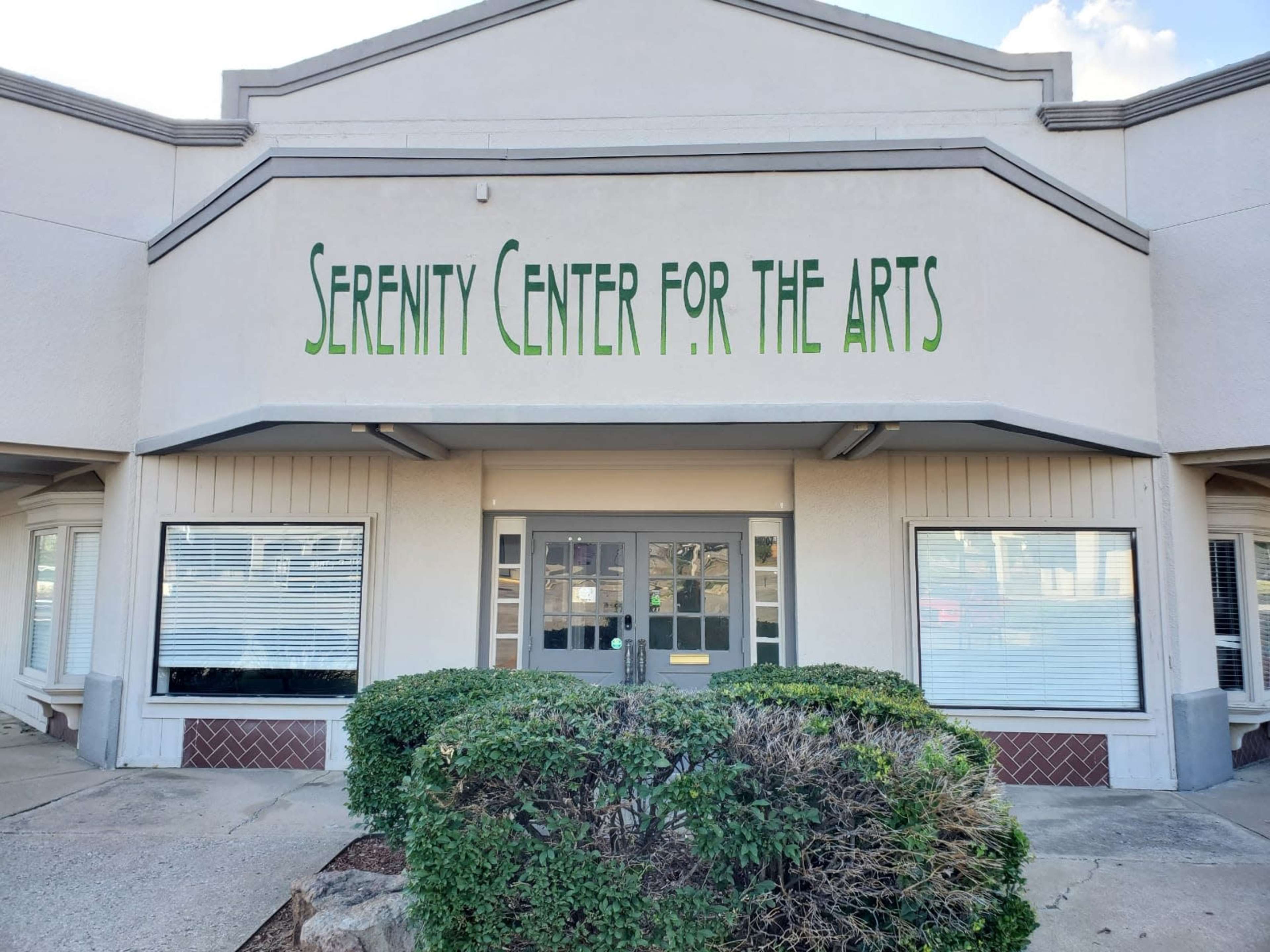 The image shows the exterior of a building labeled "Serenity Center for the Arts" with large windows covered by blinds.