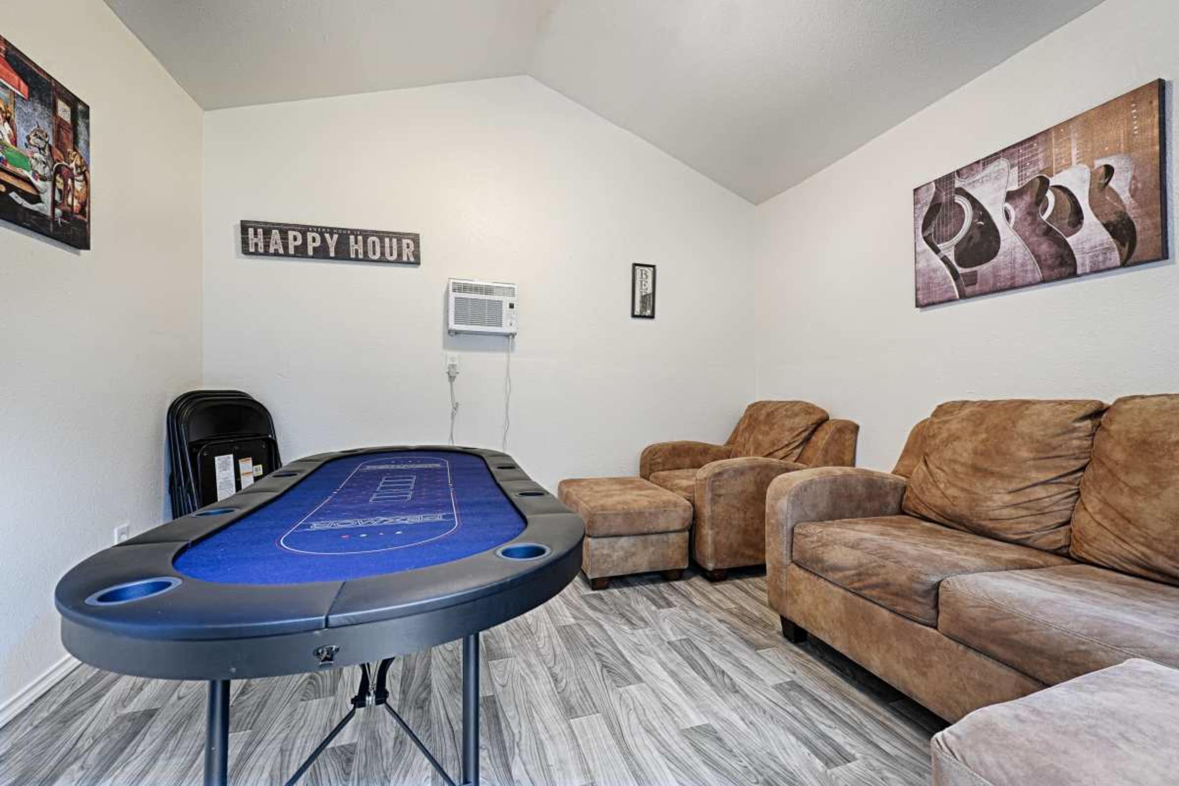 The image shows a room with a poker table, two brown chairs, and wall decorations including a "Happy Hour" sign.