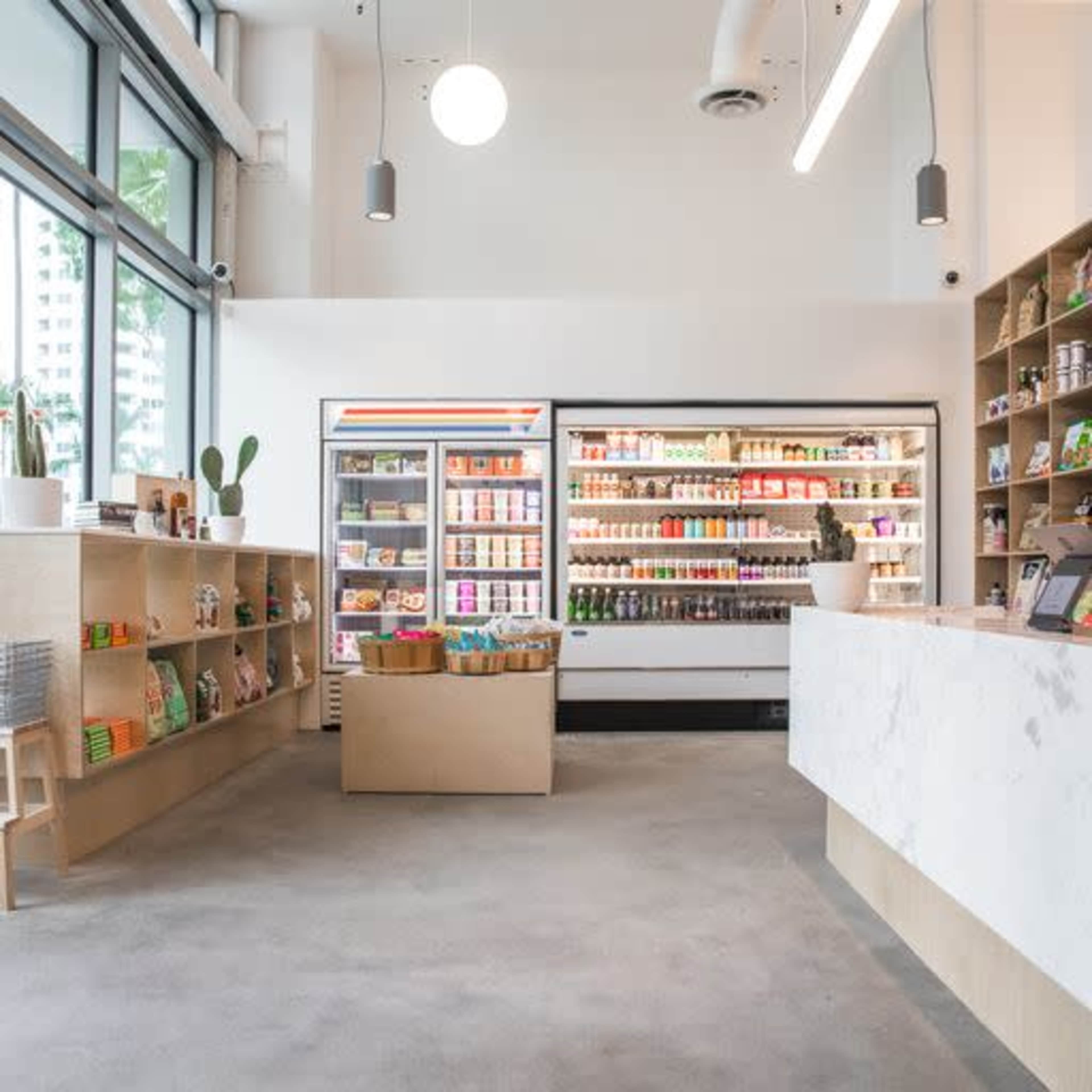 A modern retail space with neatly arranged shelves on the left and a refrigerated display on the right, all under bright overhead lights.