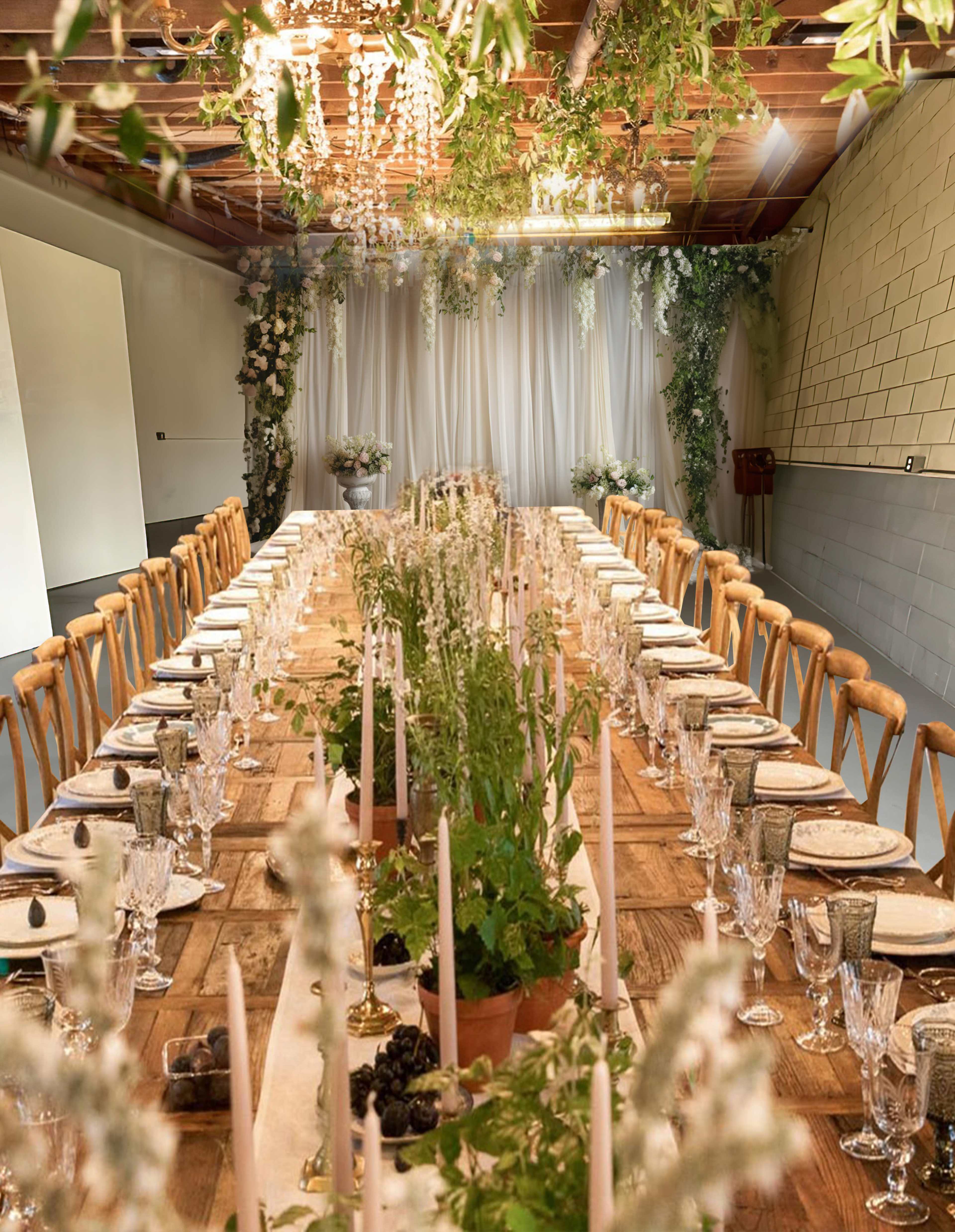 A long table is set for a formal dinner in a decorated room with greenery and candles.