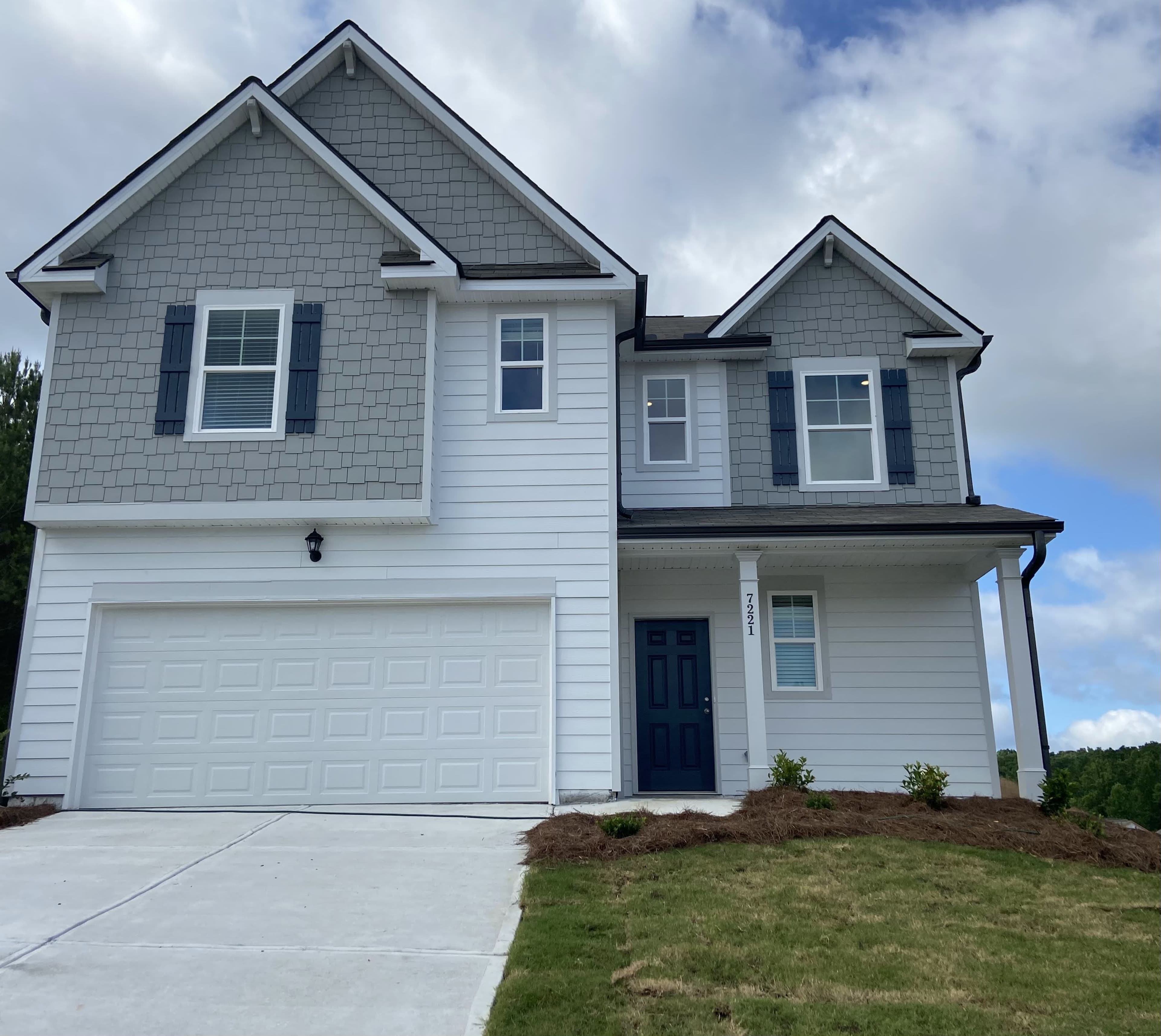 A modern two-story house with gray shingles, white siding, and a two-car garage.