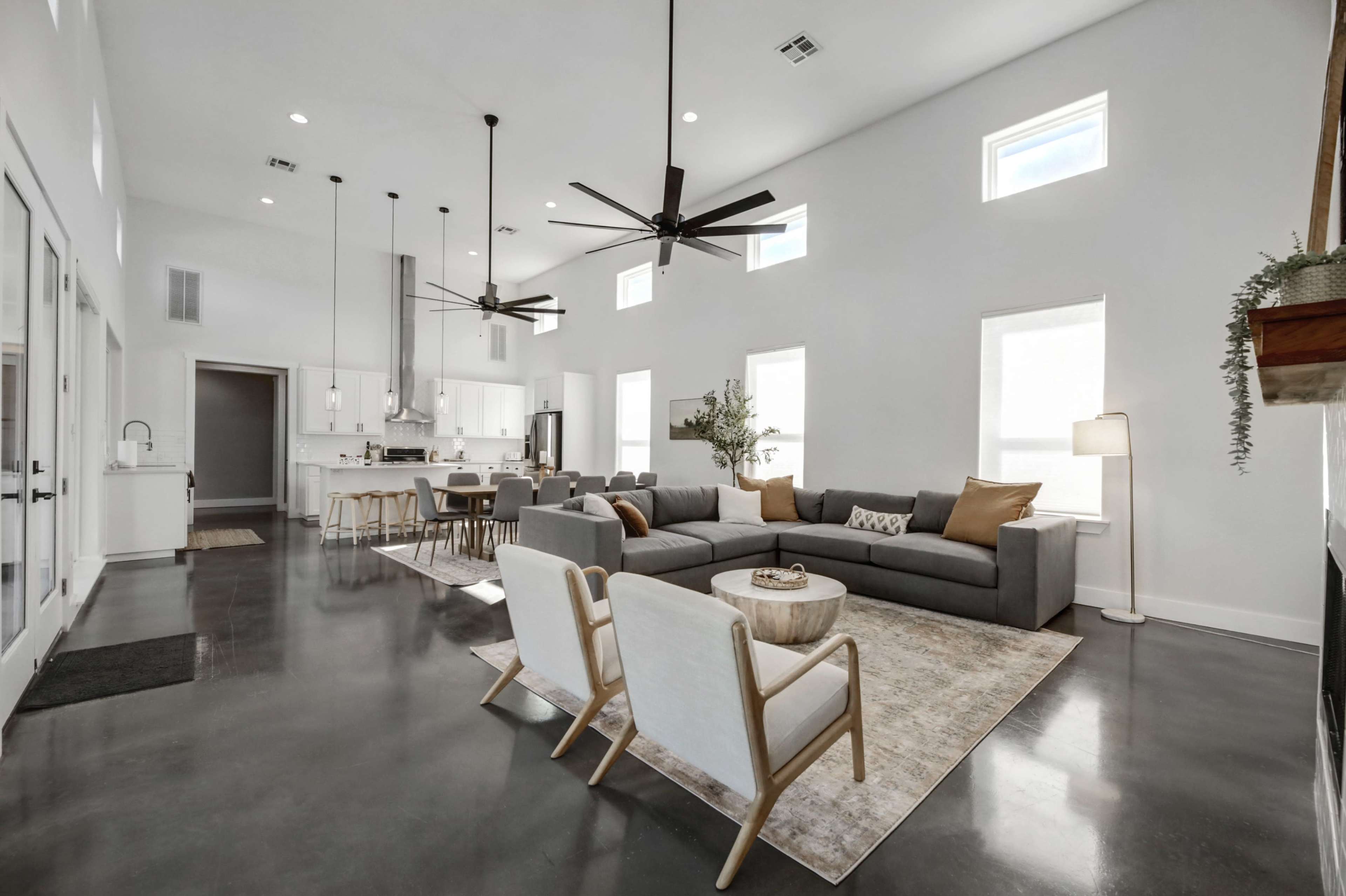 A spacious living area with modern furniture, a large sectional sofa, and a dining space featuring a kitchen in the background.