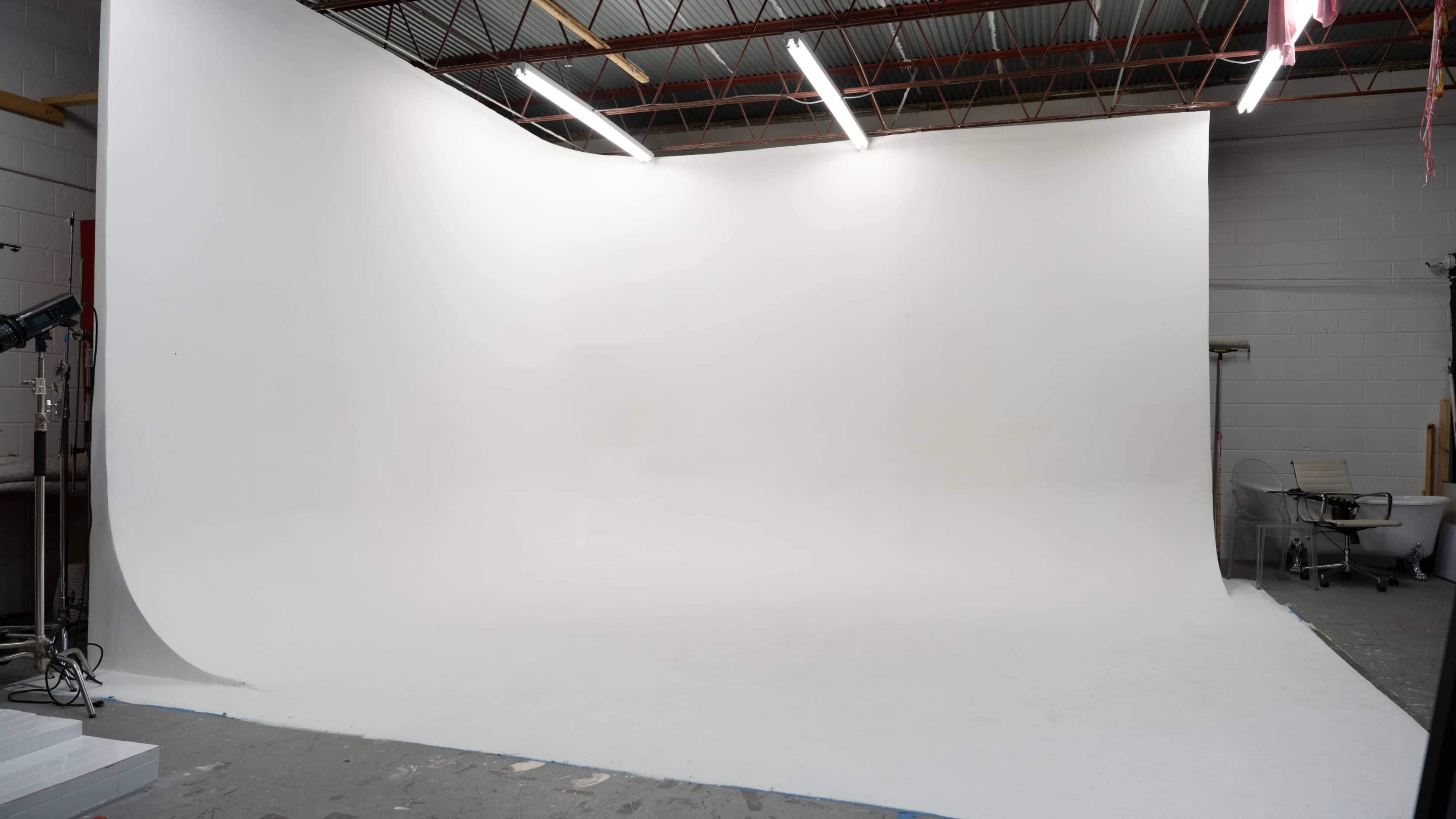 A large photography studio with a seamless white backdrop and overhead lights.