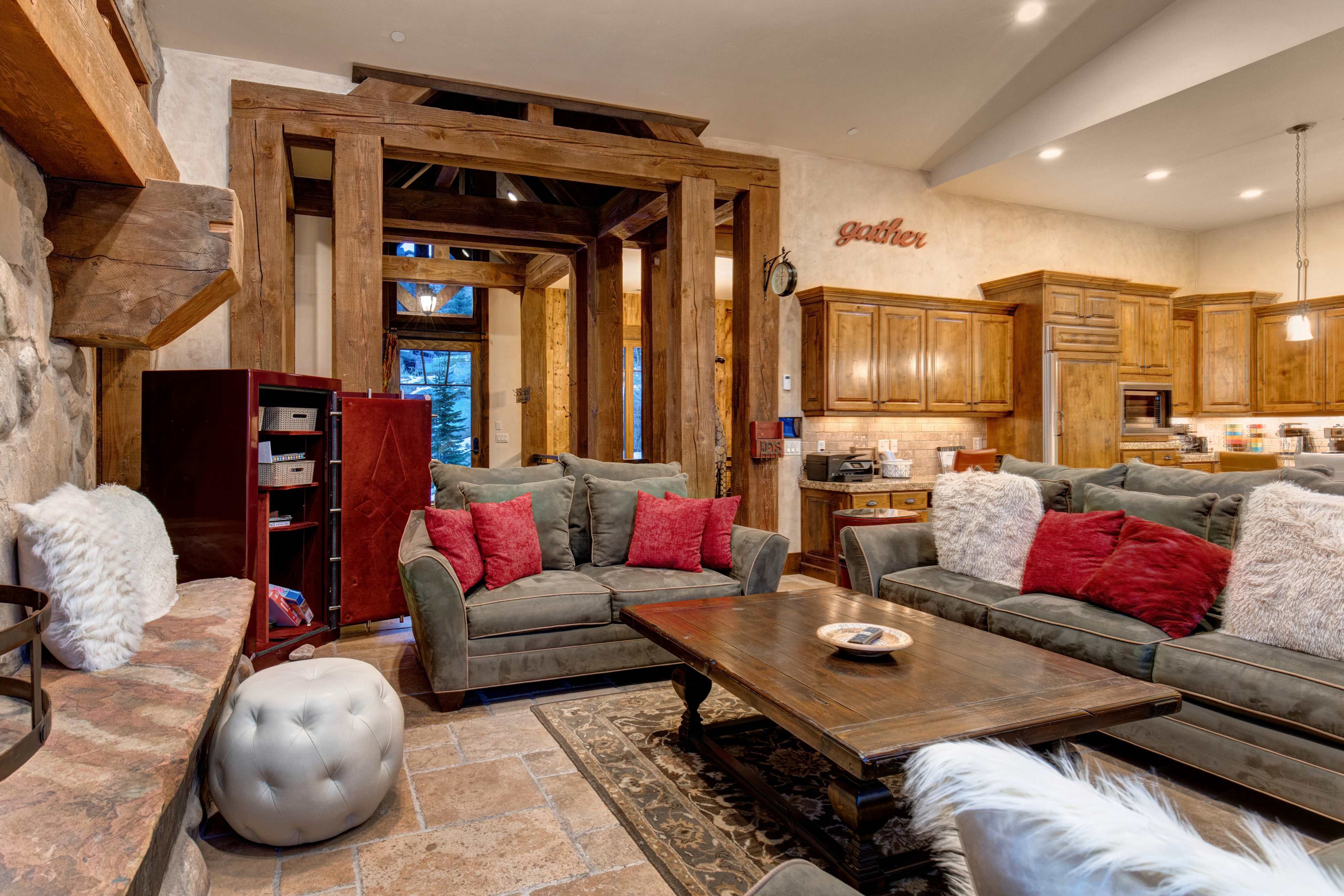 The living room features a warm, inviting layout with gray sofas, a wooden coffee table, and rustic decor elements.