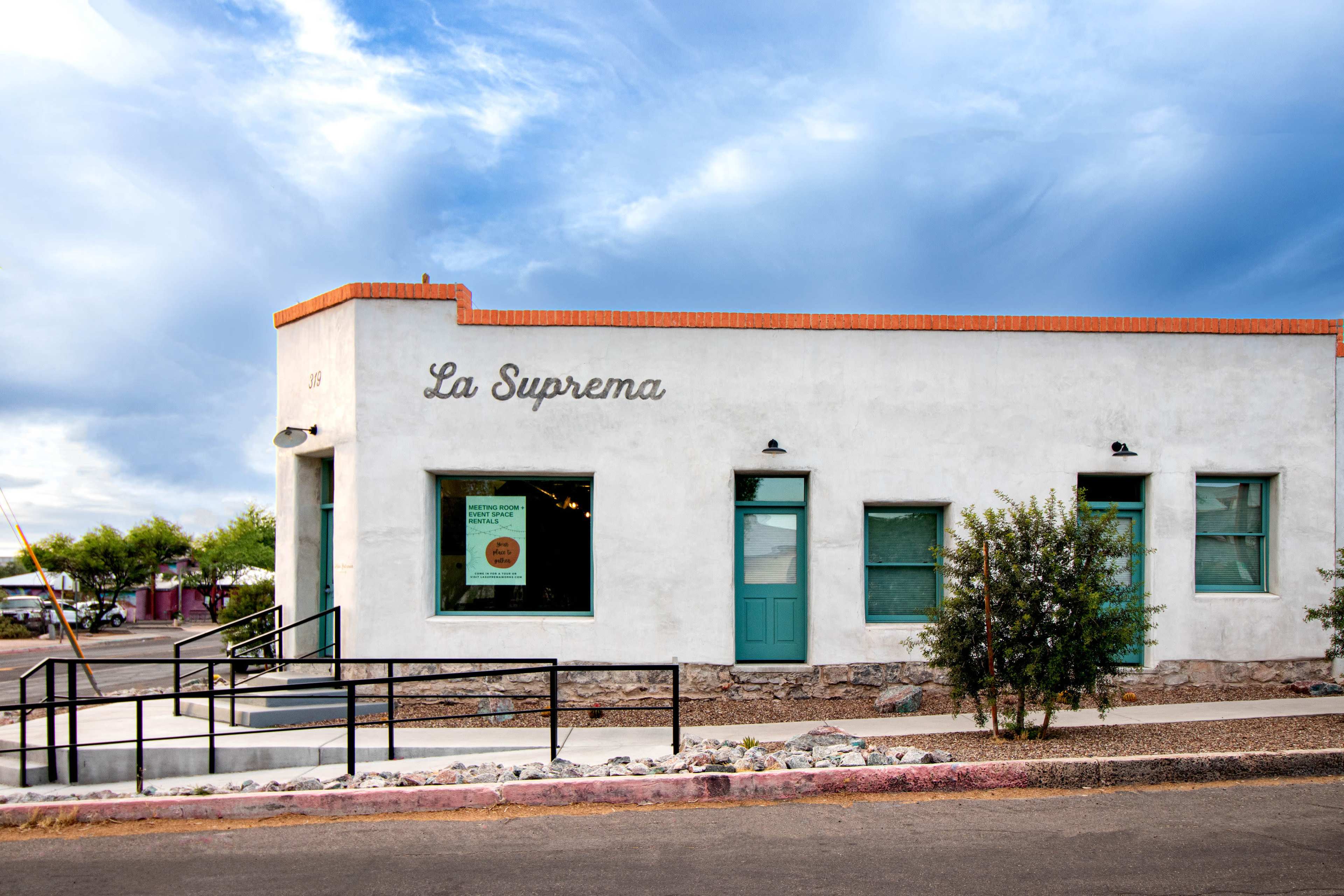 A white stucco building with green doors and windows, labeled "La Suprema."