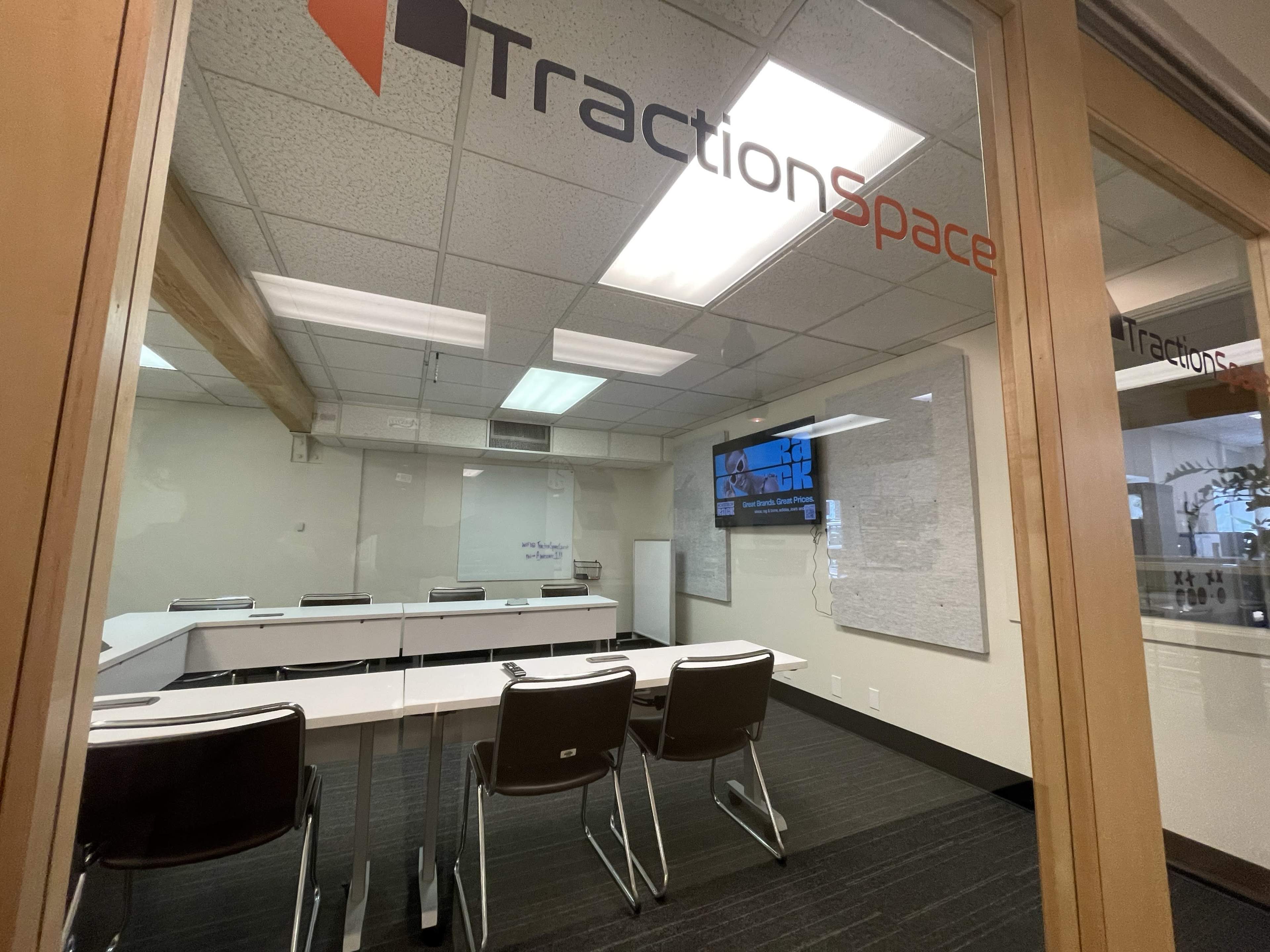 A conference room labeled "TractionSpace" with a large table and several chairs, located behind glass walls.
