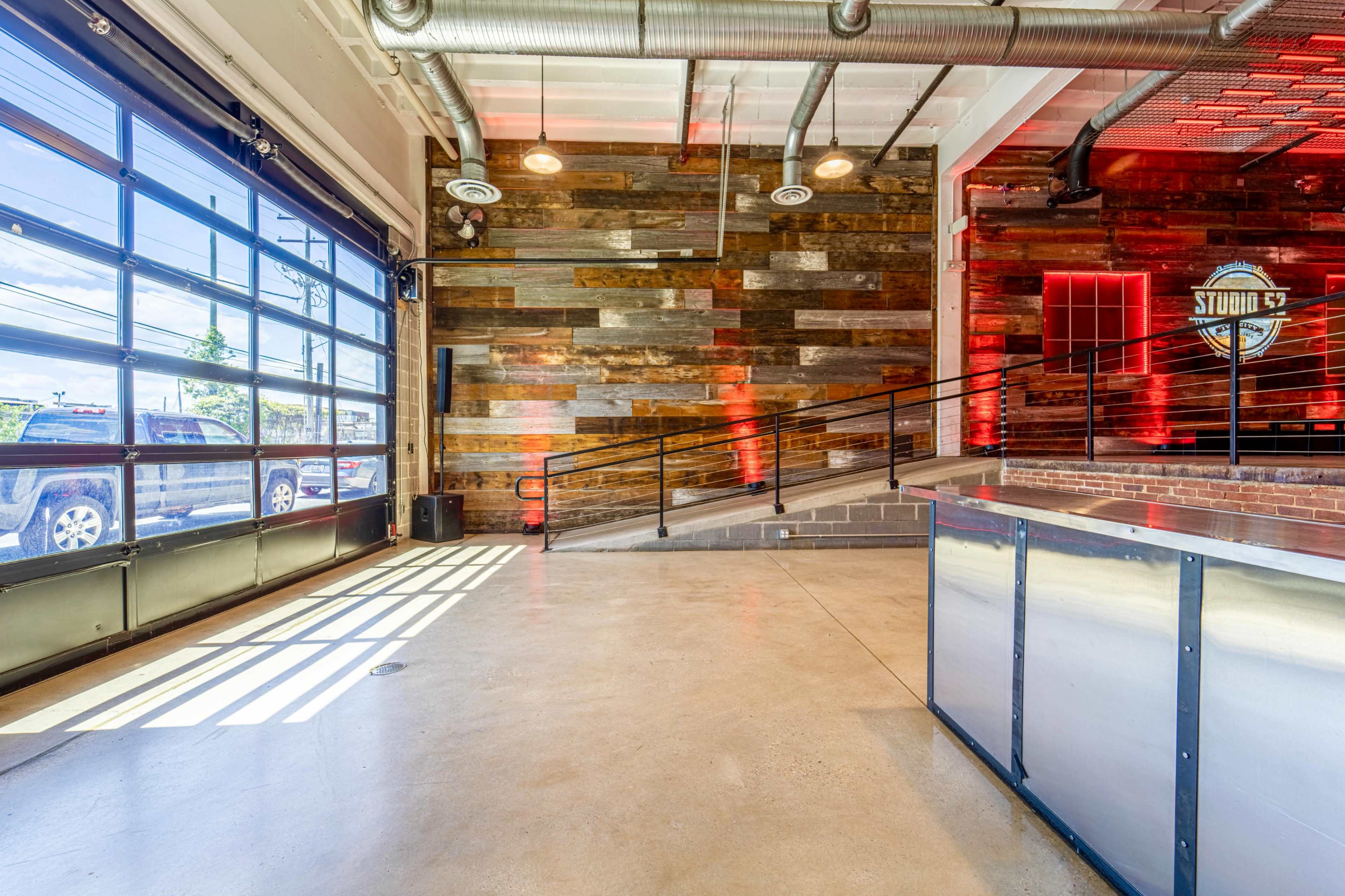 A modern interior space with a polished concrete floor, a wooden accent wall, and large windows allowing natural light to enter.