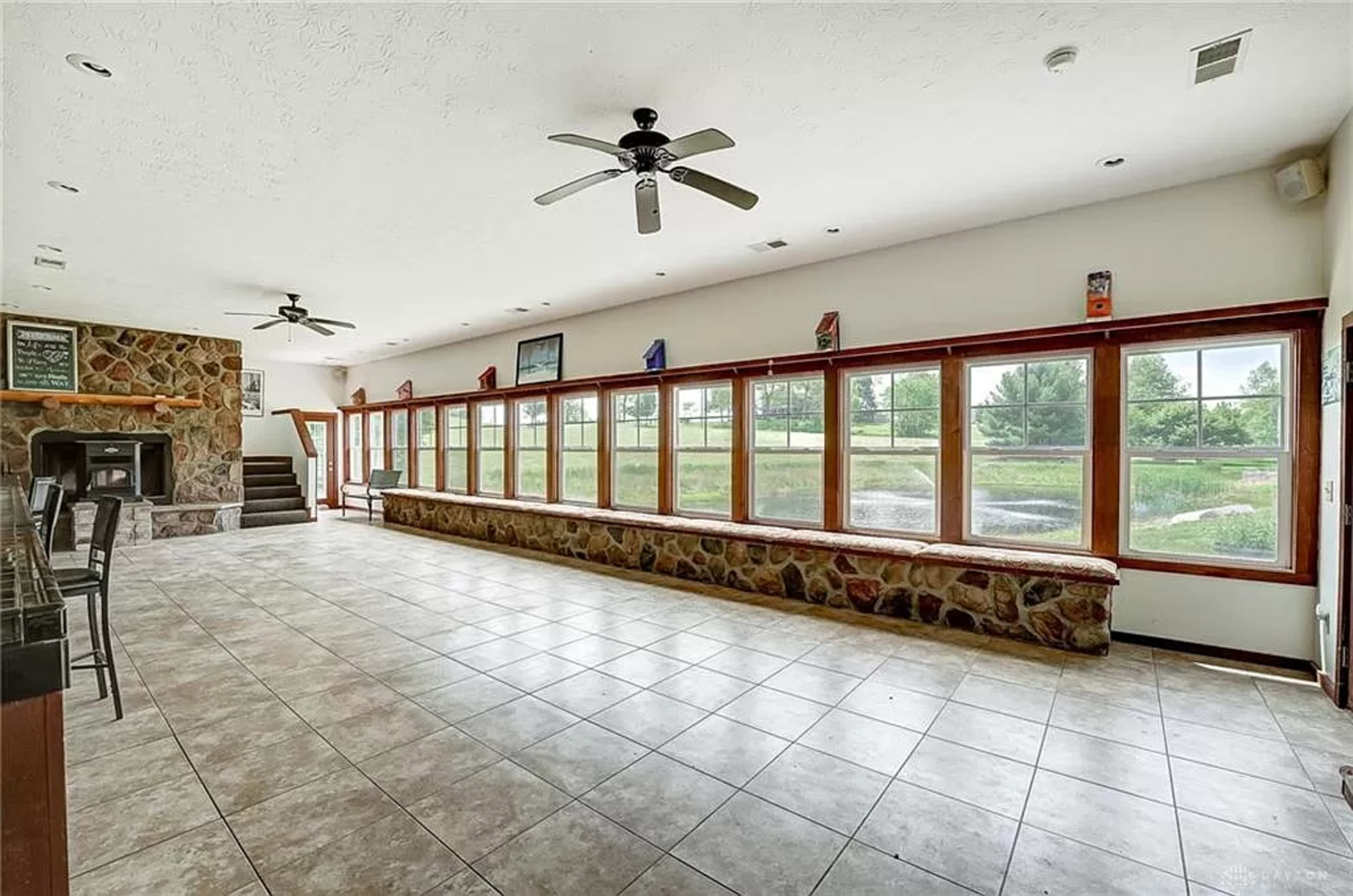 The spacious interior features a stone wall fireplace and large windows that fill the room with natural light.