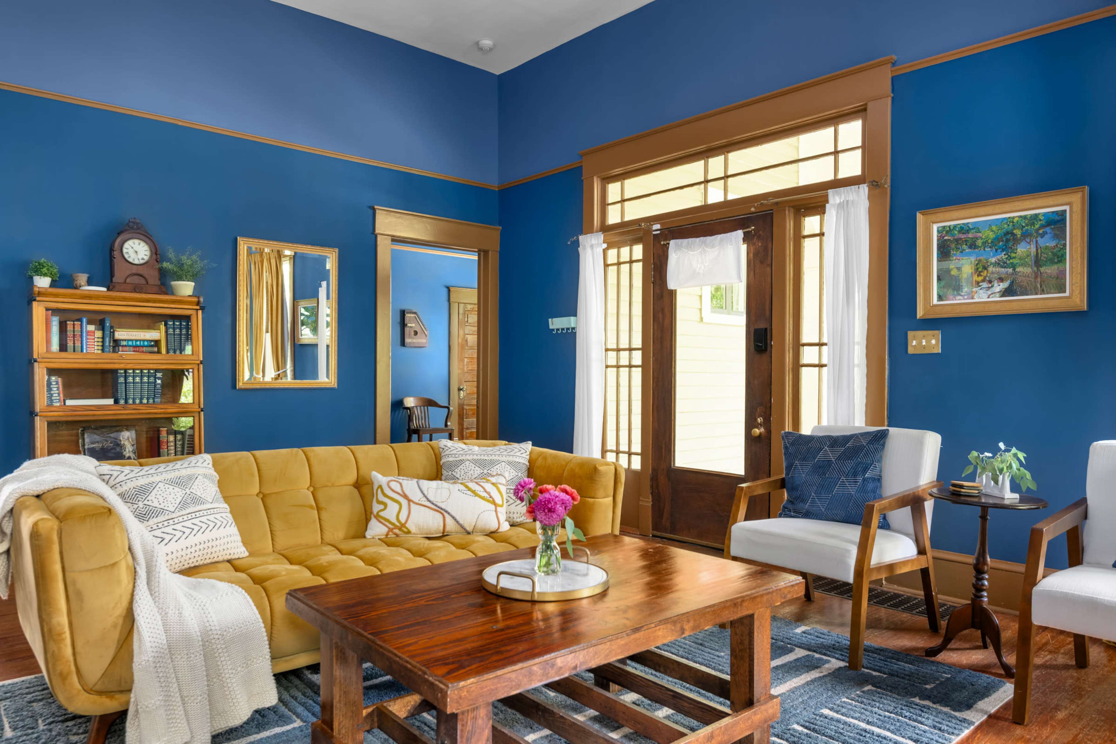 The living room features a yellow couch, a wooden coffee table, and blue walls adorned with decorative accents and wood trim.