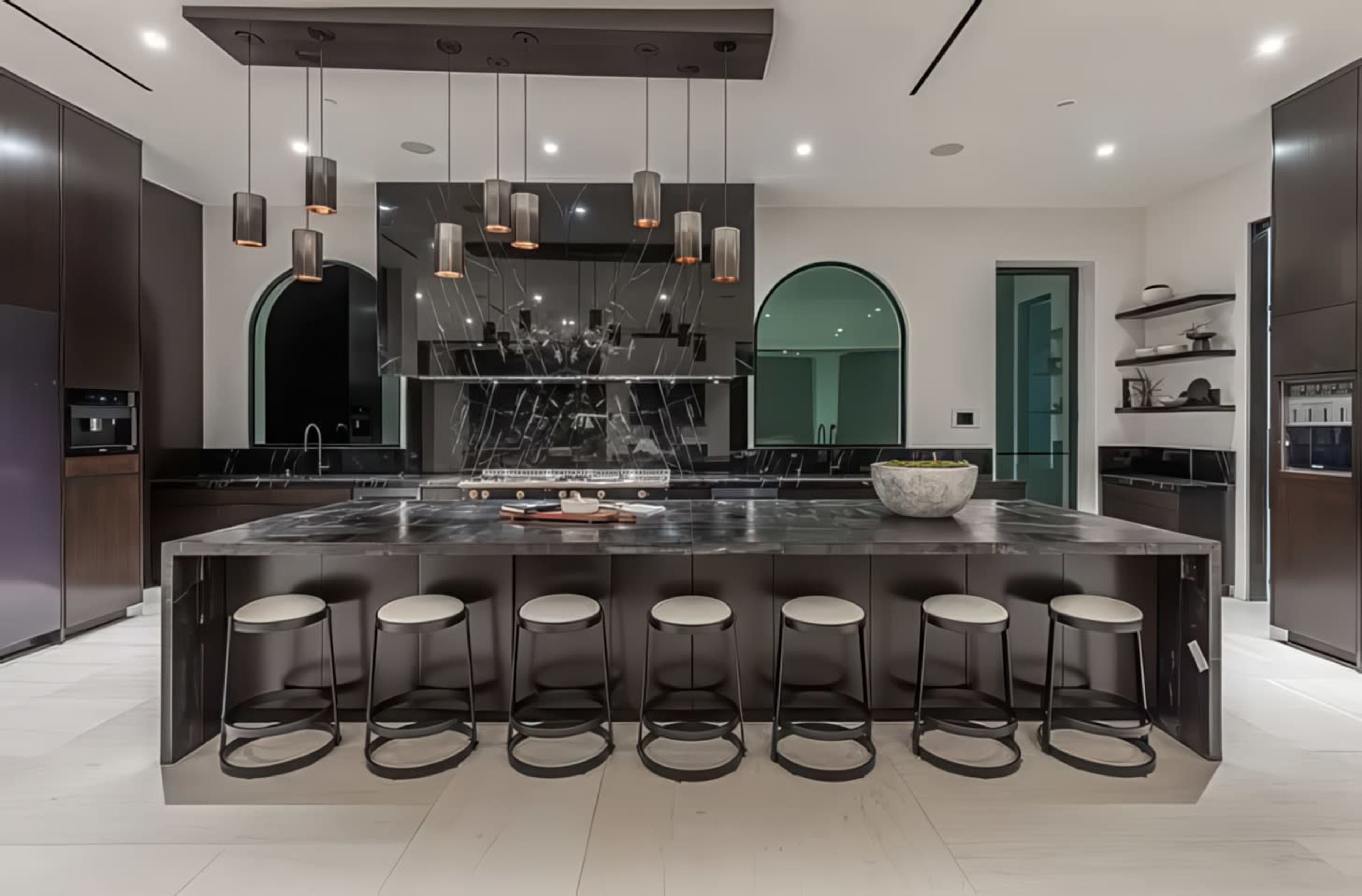 The image shows a modern kitchen featuring a large island with seating, sleek cabinetry, and pendant lighting.