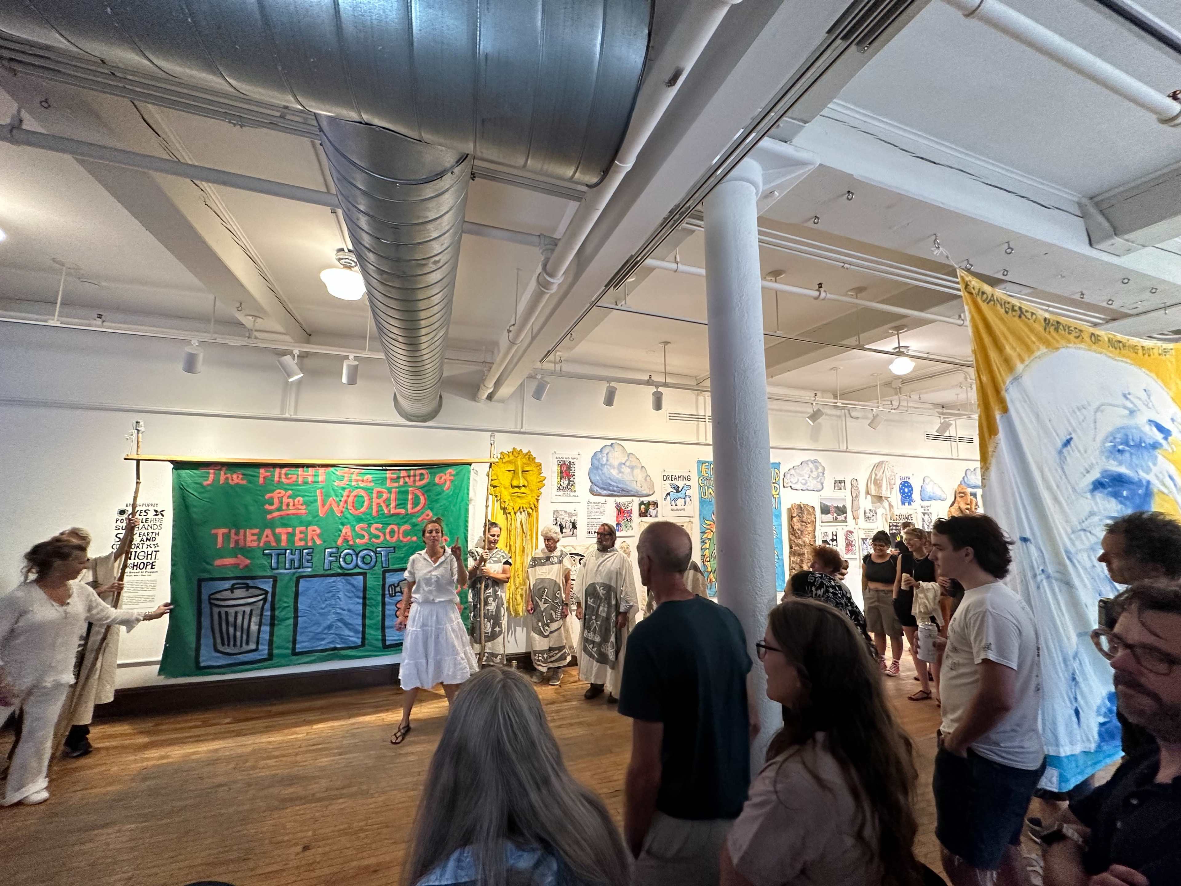 A group of people gathers in an art gallery featuring large banners and paintings on the walls.