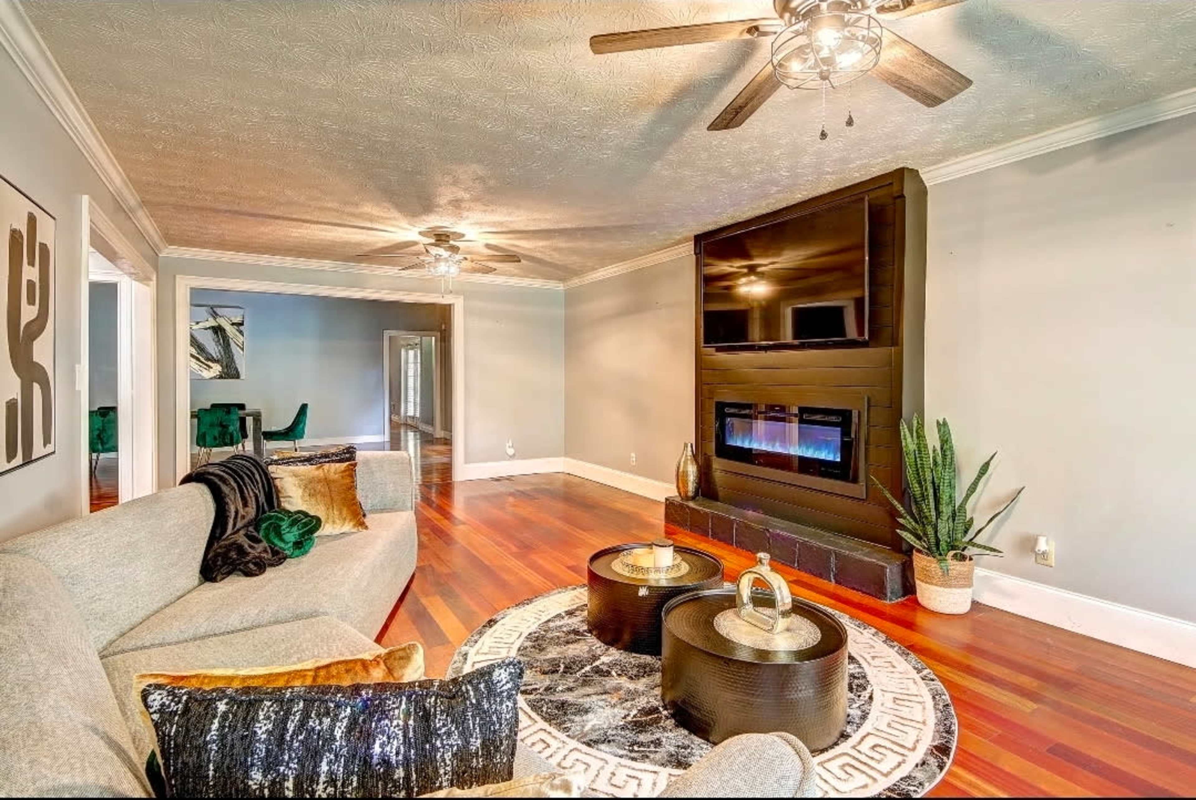 The image shows a spacious living room with a modern fireplace, a comfortable sectional sofa, and wooden flooring.
