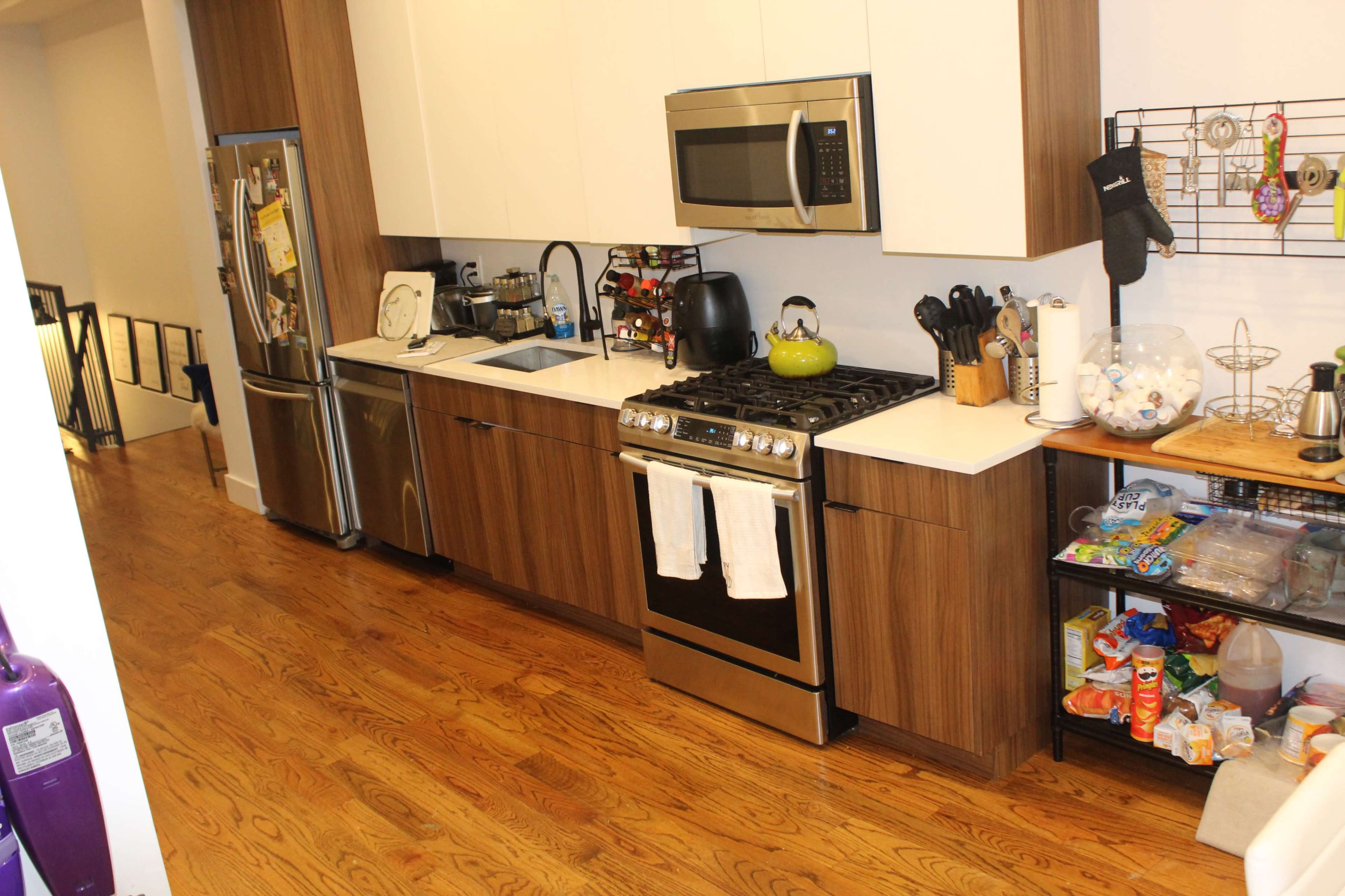 A modern kitchen with wooden cabinets, stainless steel appliances, and a countertop with various kitchen tools and utensils.