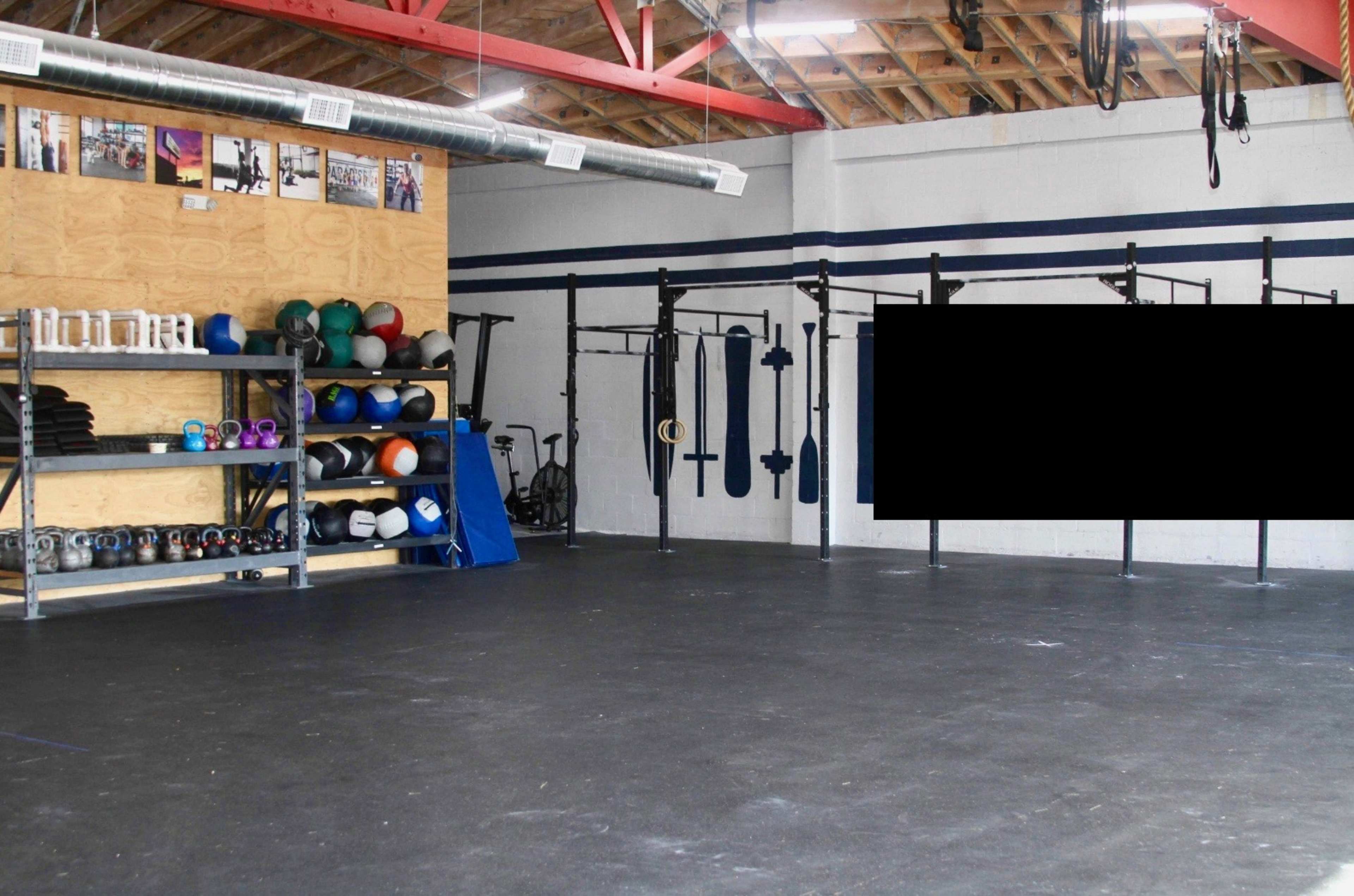 A spacious gym interior with shelves of fitness equipment on the left and gym apparatus mounted on the walls.