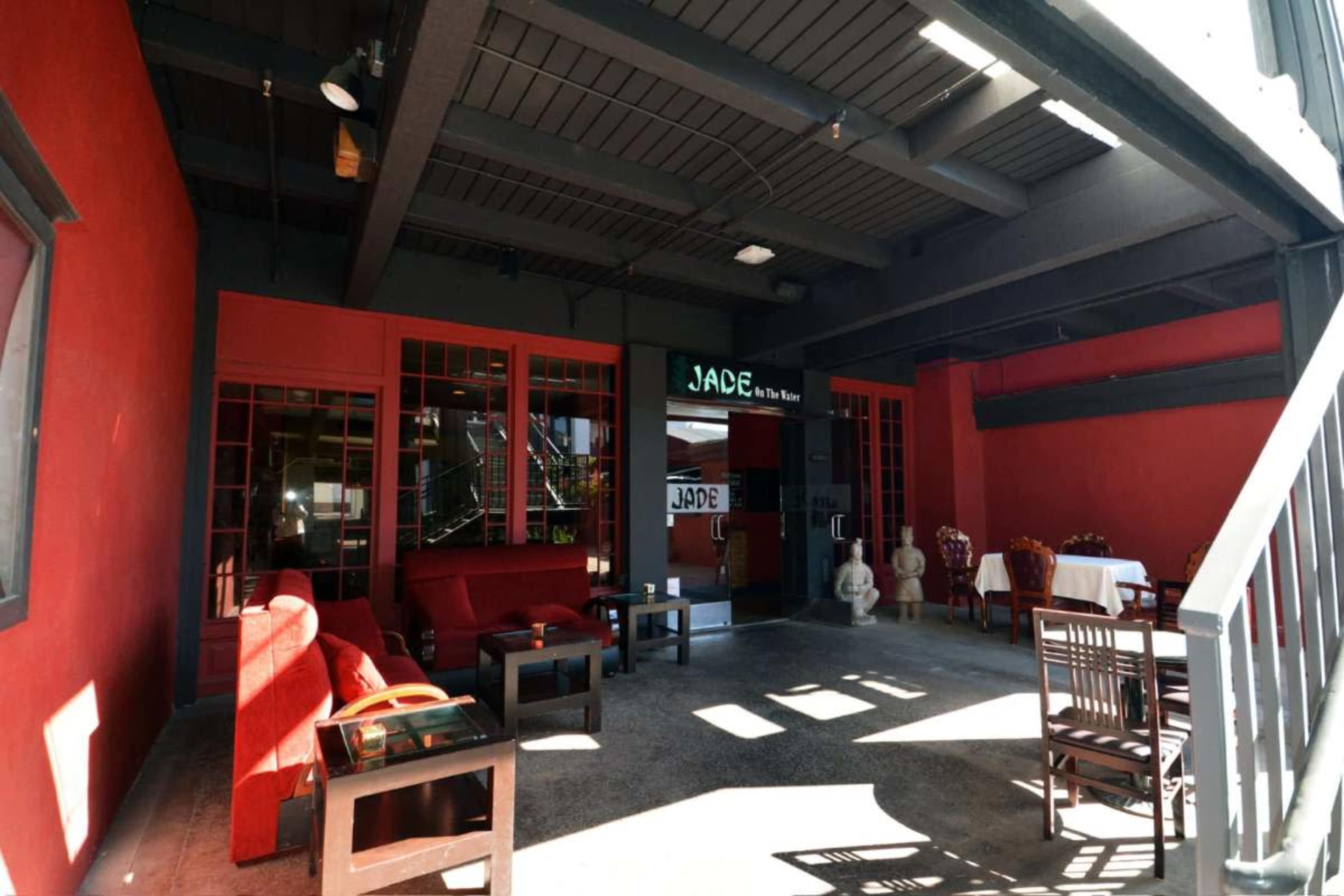 A spacious dining area with red walls, a few wooden tables and chairs, and a staircase in the background.