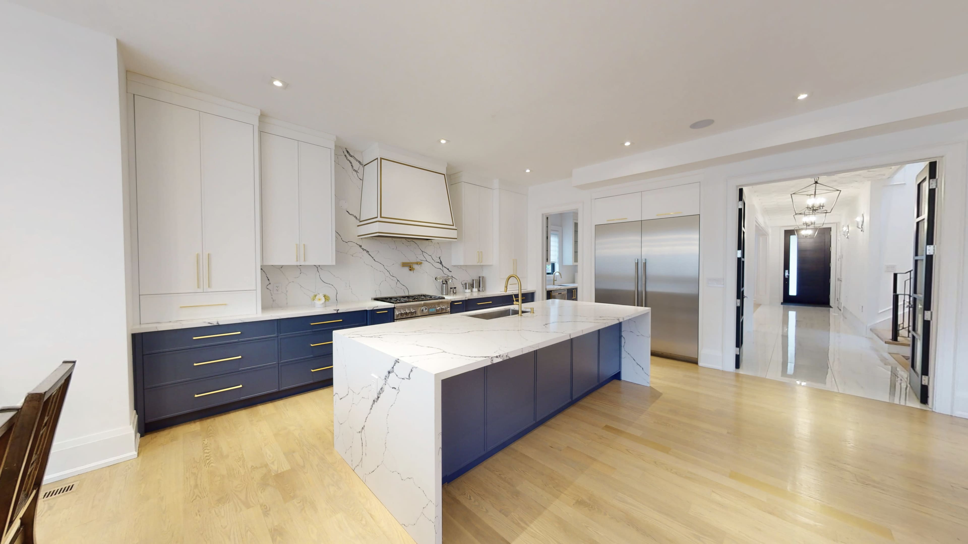 The kitchen features an island with a marble countertop, navy blue cabinetry, and stainless steel appliances, creating an open and modern layout.