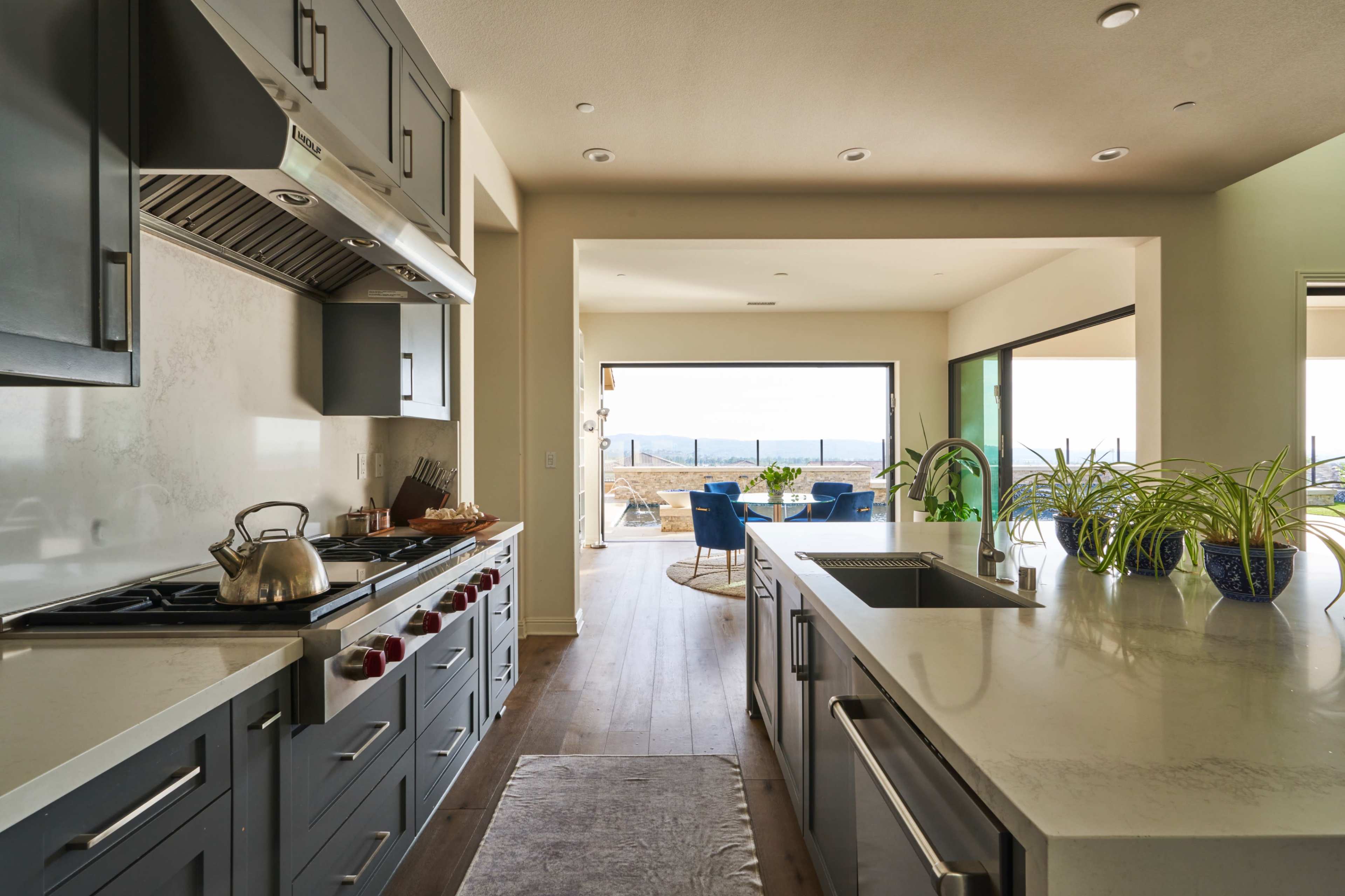 A modern kitchen features stainless steel appliances and a view of a living area with outdoor seating.