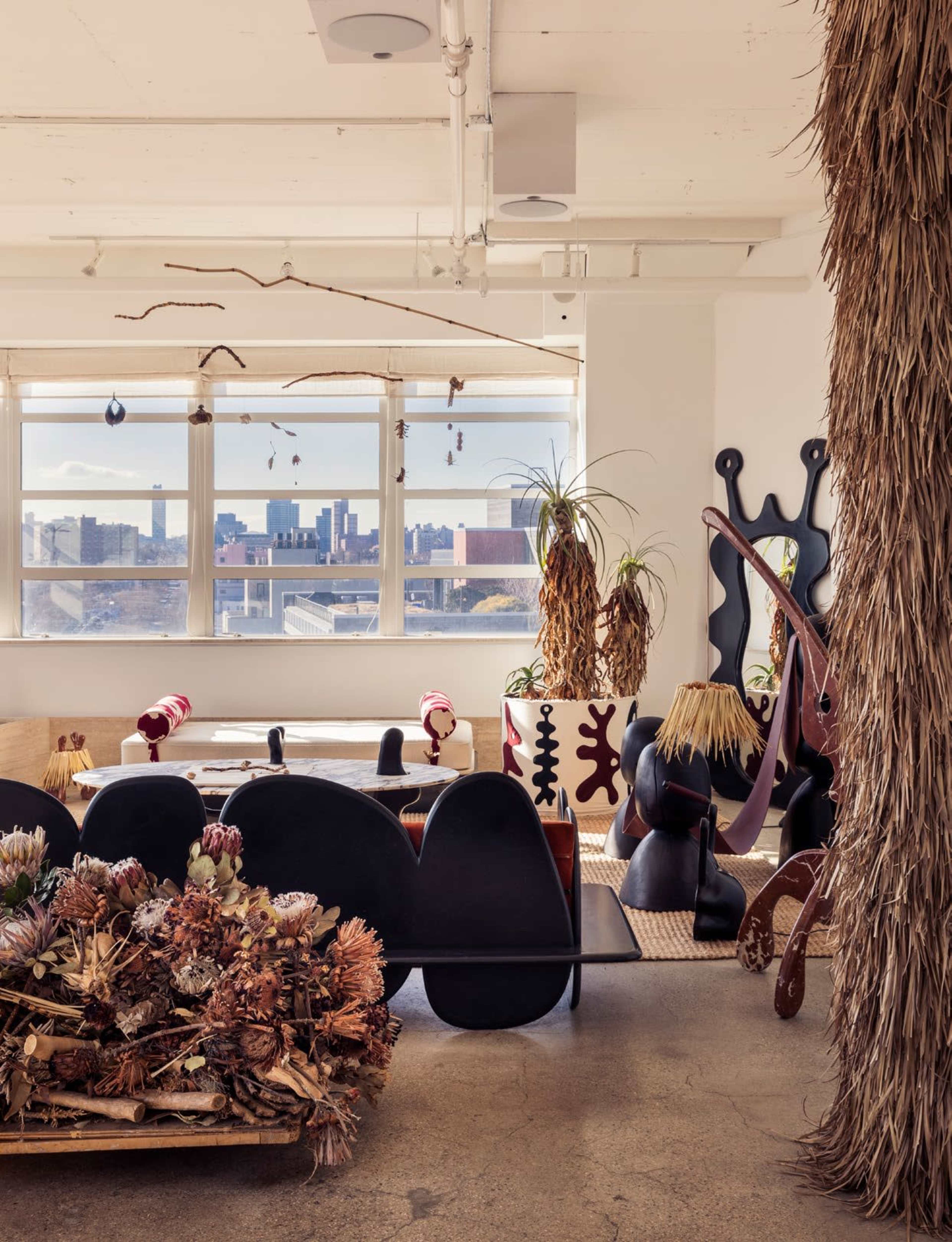 The image showcases a trendy interior space featuring eclectic furniture and decor, large windows with a city skyline view, and various plants throughout.