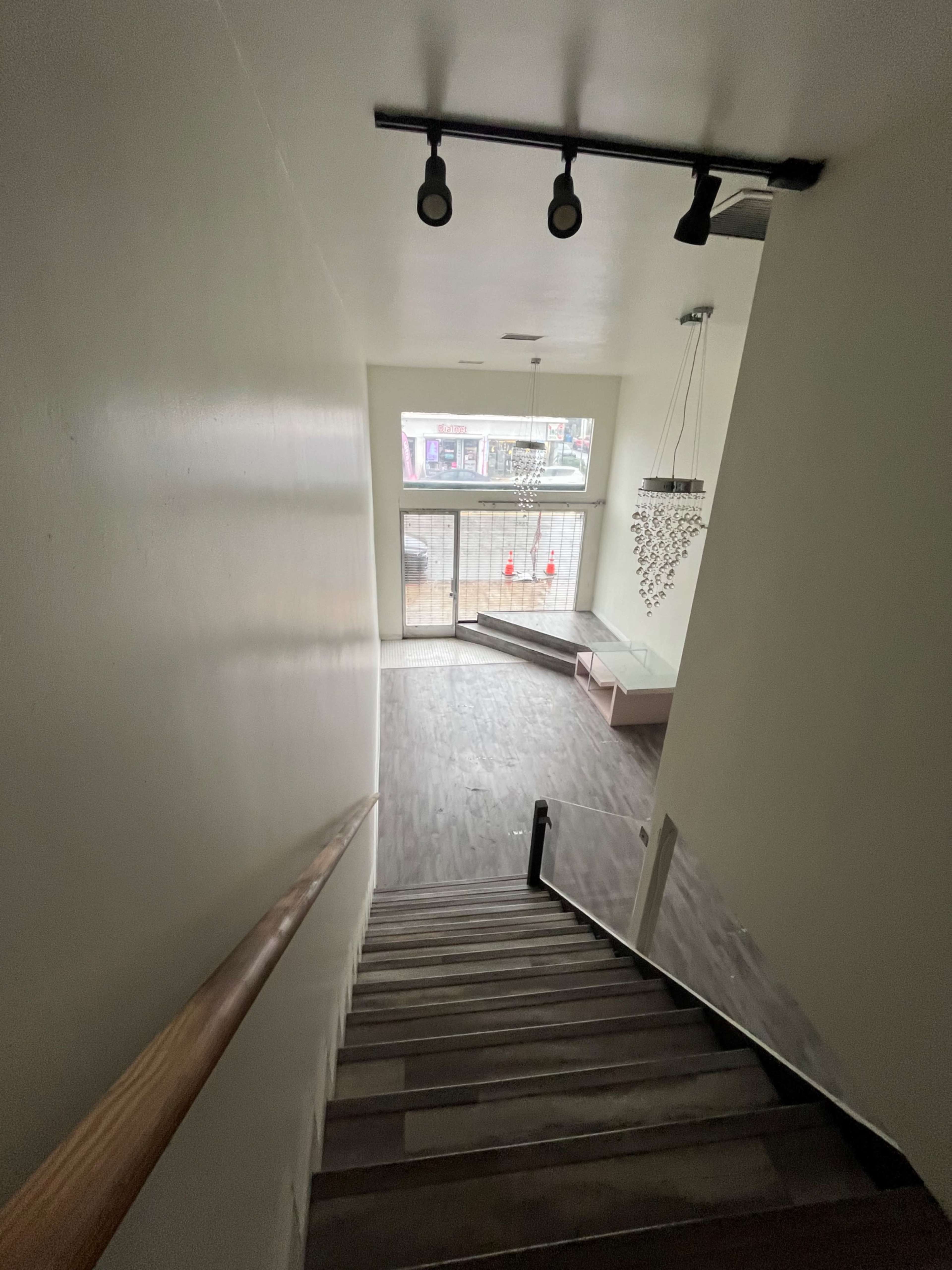 A staircase leads down to a spacious room with large windows and modern decor.