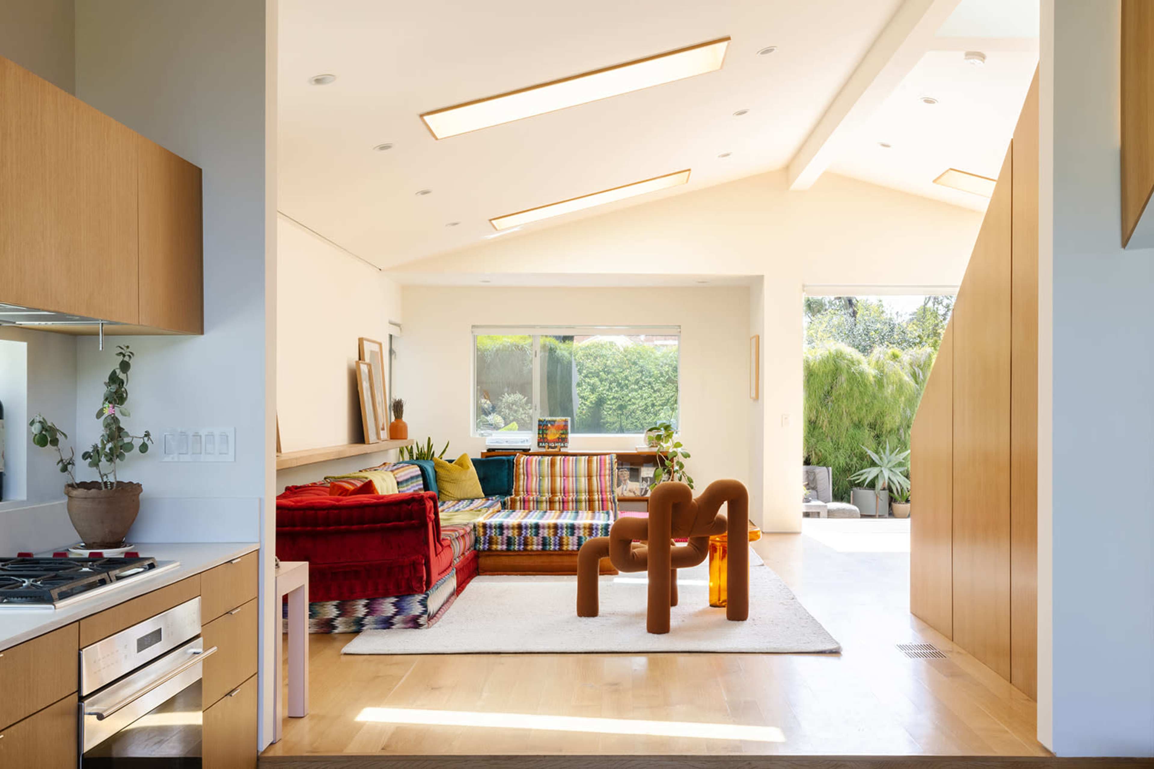 An open-concept living space featuring a colorful sofa, a modern coffee table, and large windows allowing natural light to illuminate the room.