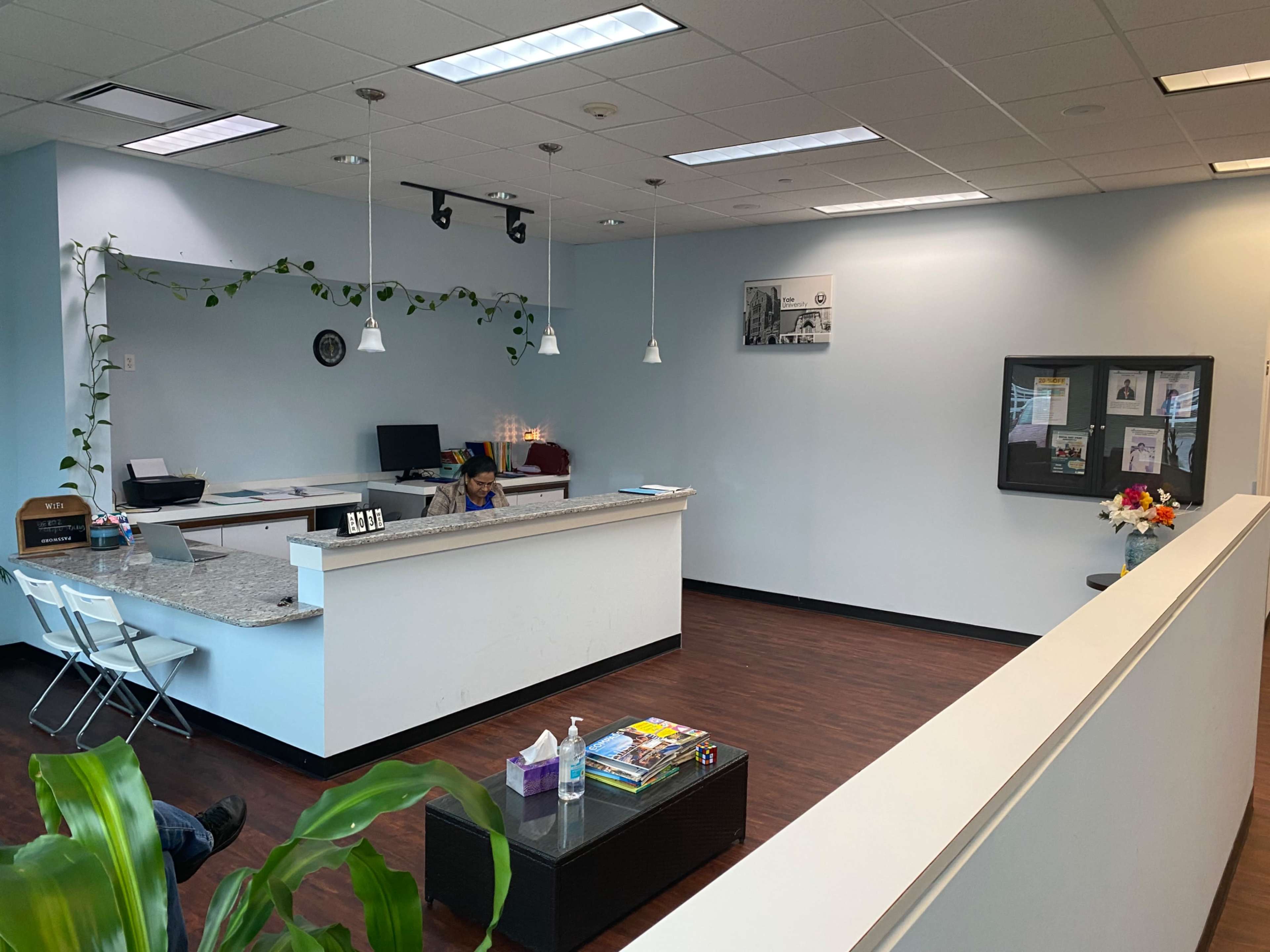 A modern reception area with a front desk, seating, and decorative plants.
