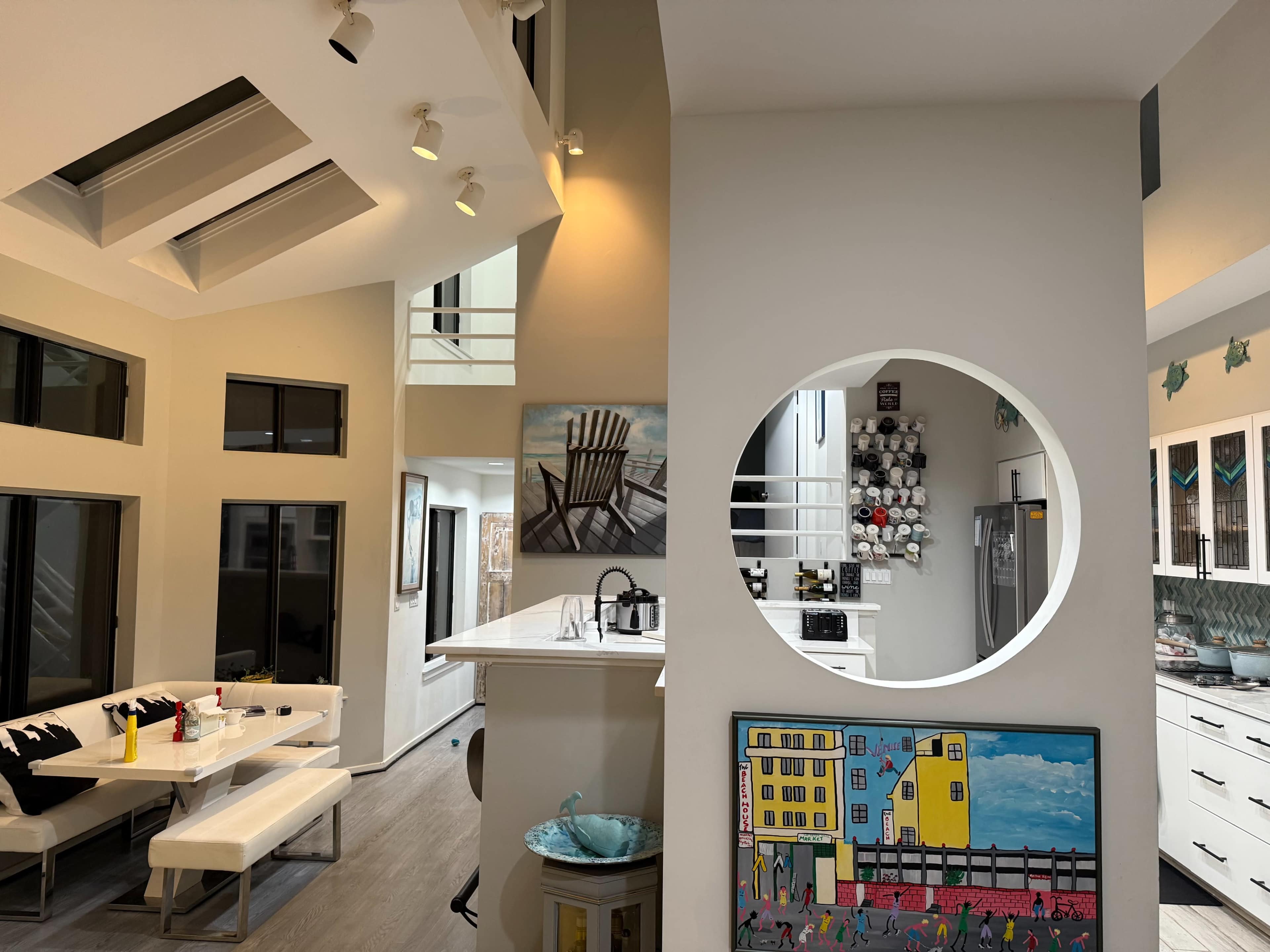The image shows an open-concept kitchen and dining area with modern decor and large windows allowing natural light.