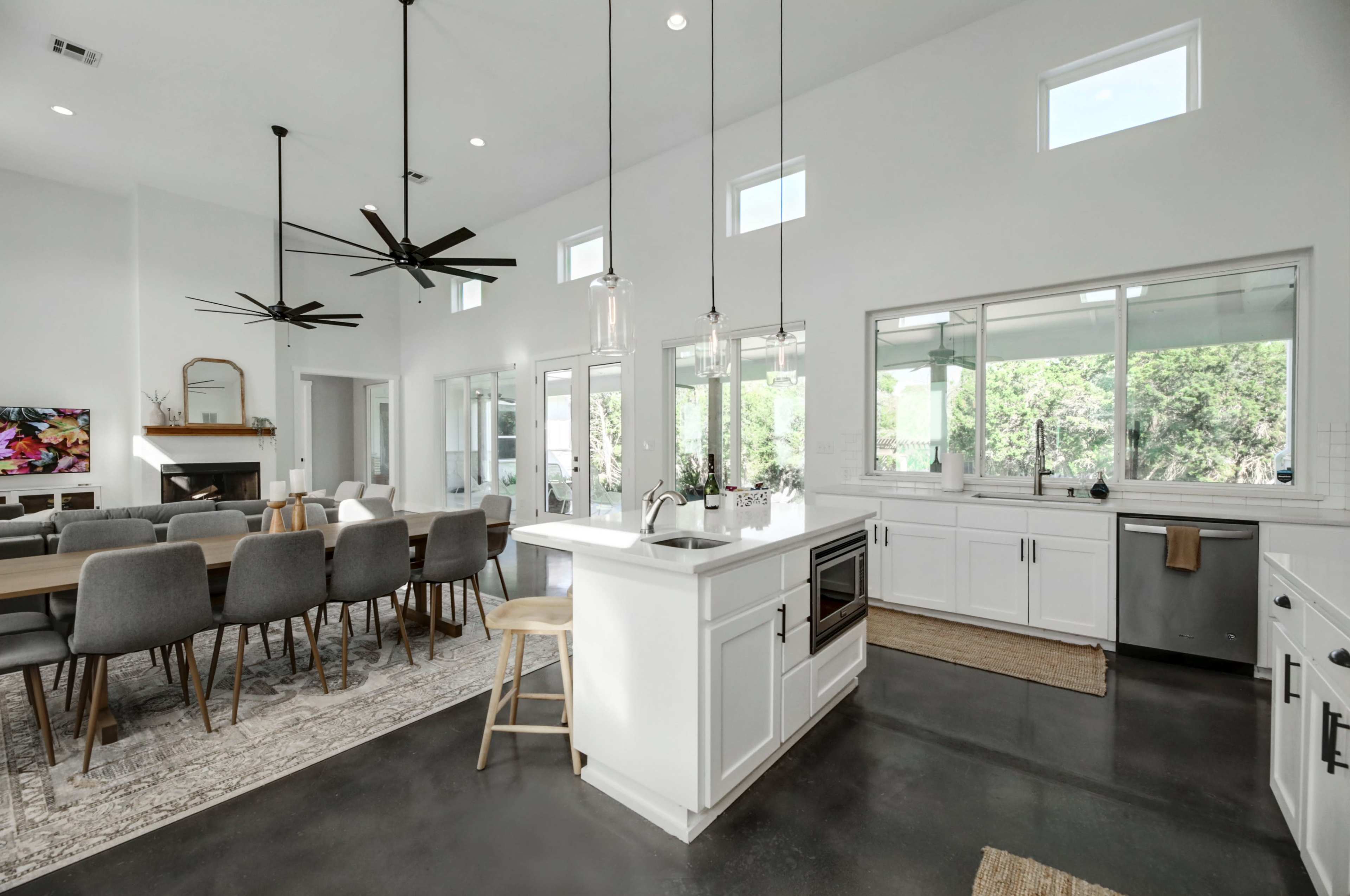 A spacious modern kitchen and dining area with white cabinetry, a large dining table, and ample natural light from multiple windows.