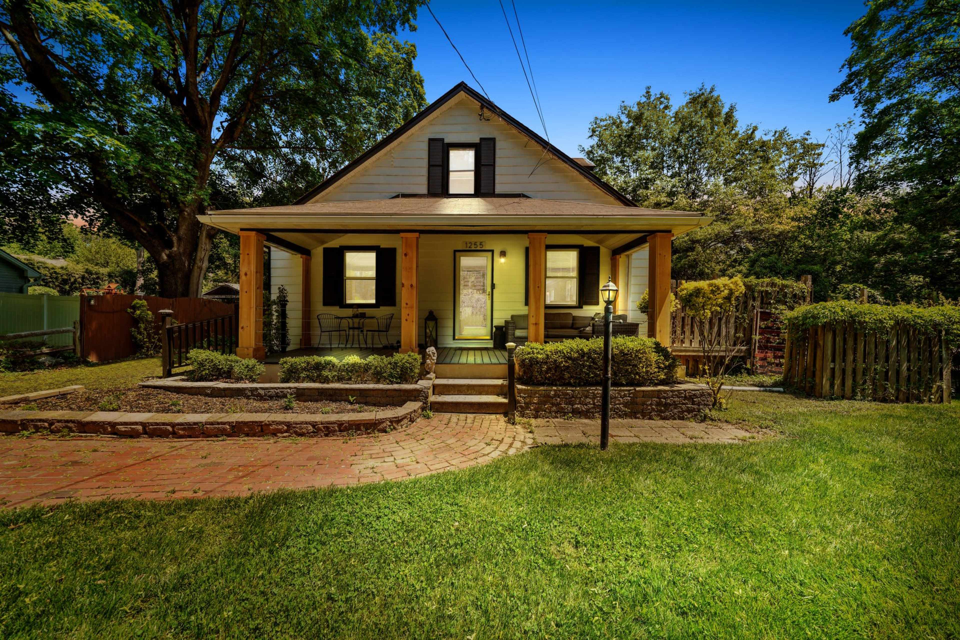 A two-story house with a front porch, surrounded by a well-maintained lawn and garden.