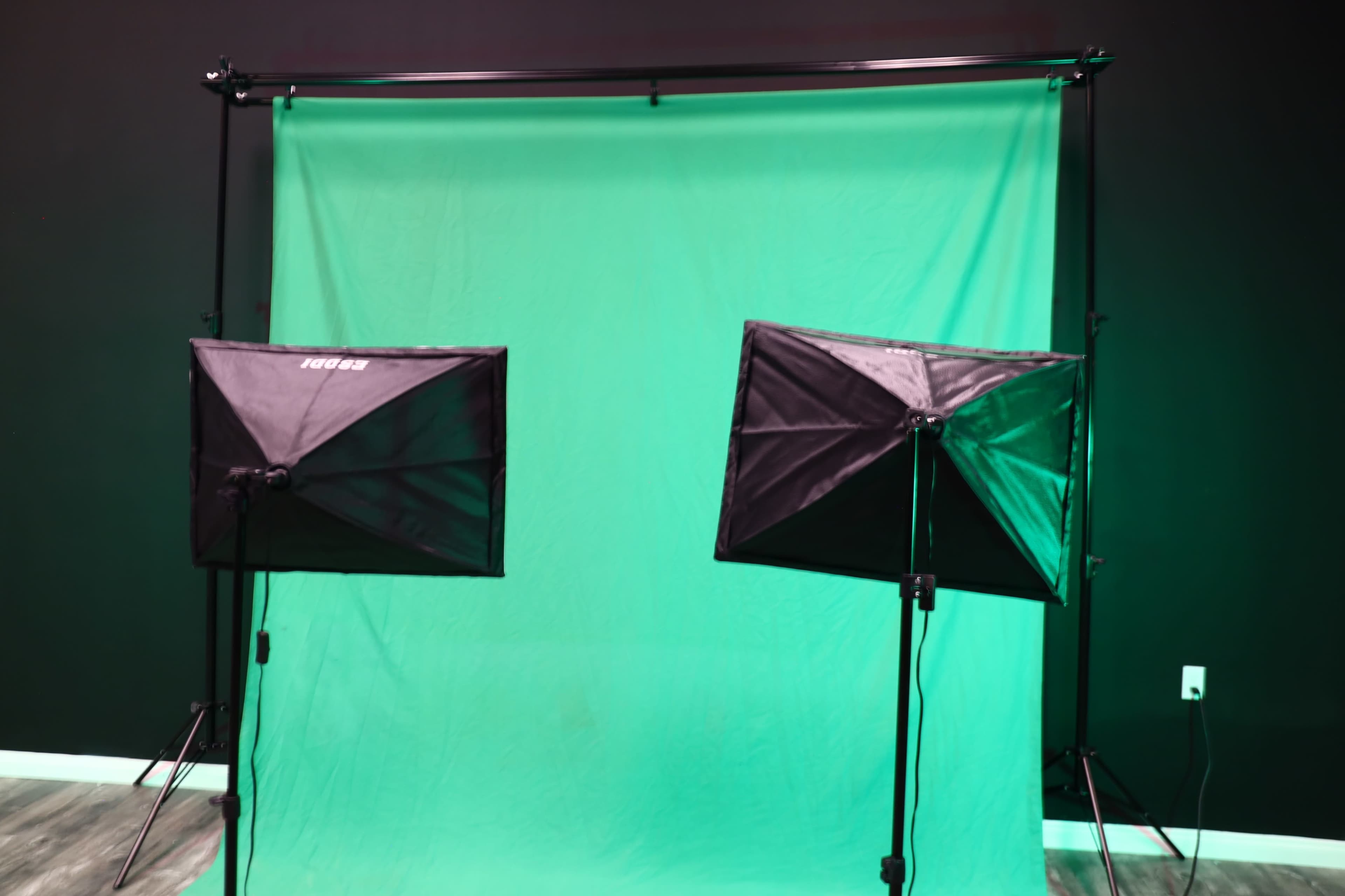 The image shows two softbox lights on stands set up in front of a green backdrop.