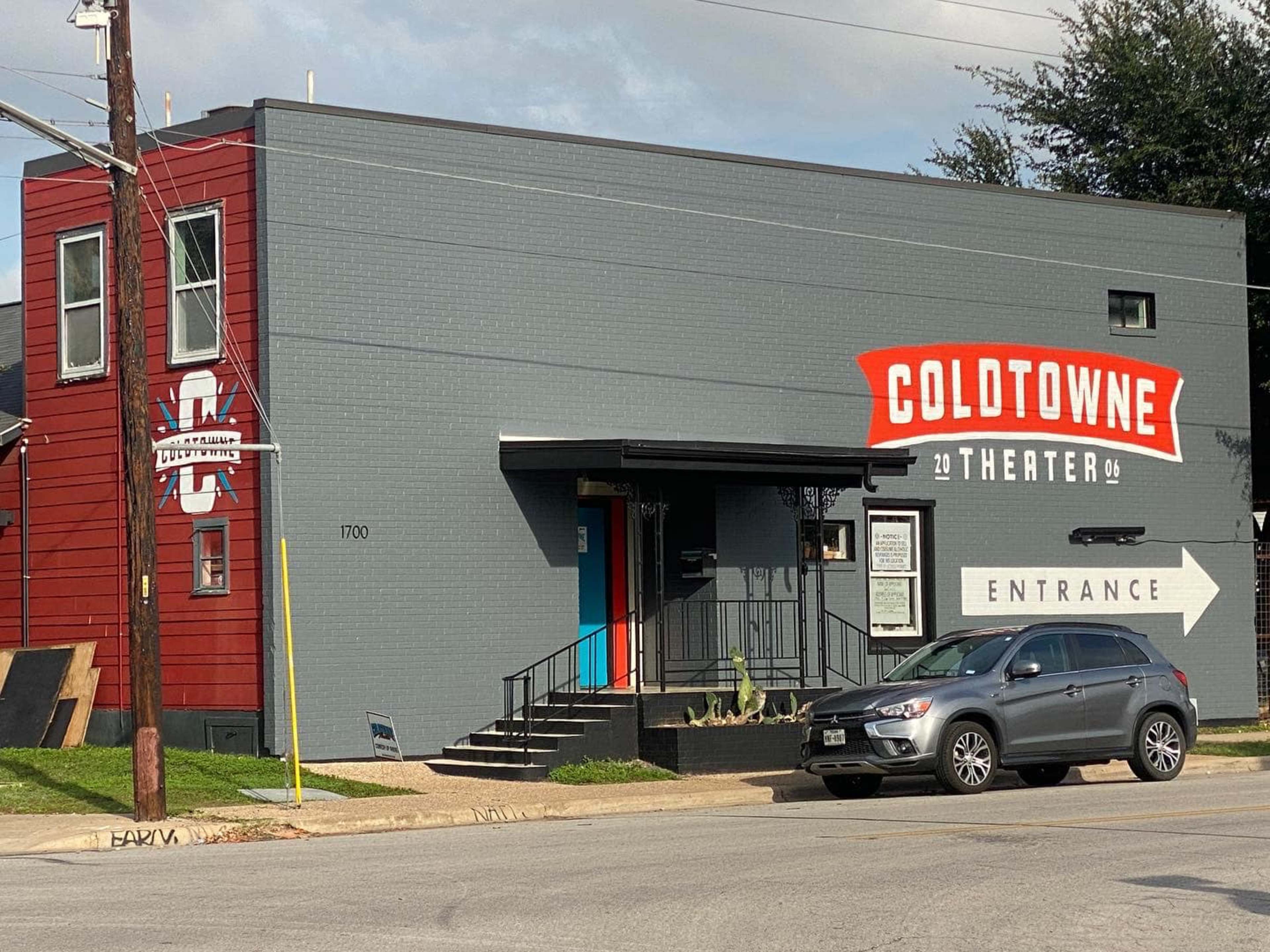The image shows a building with a gray exterior and red accents, featuring a sign that reads "COLDTOWN THEATER" and an arrow pointing to the entrance.