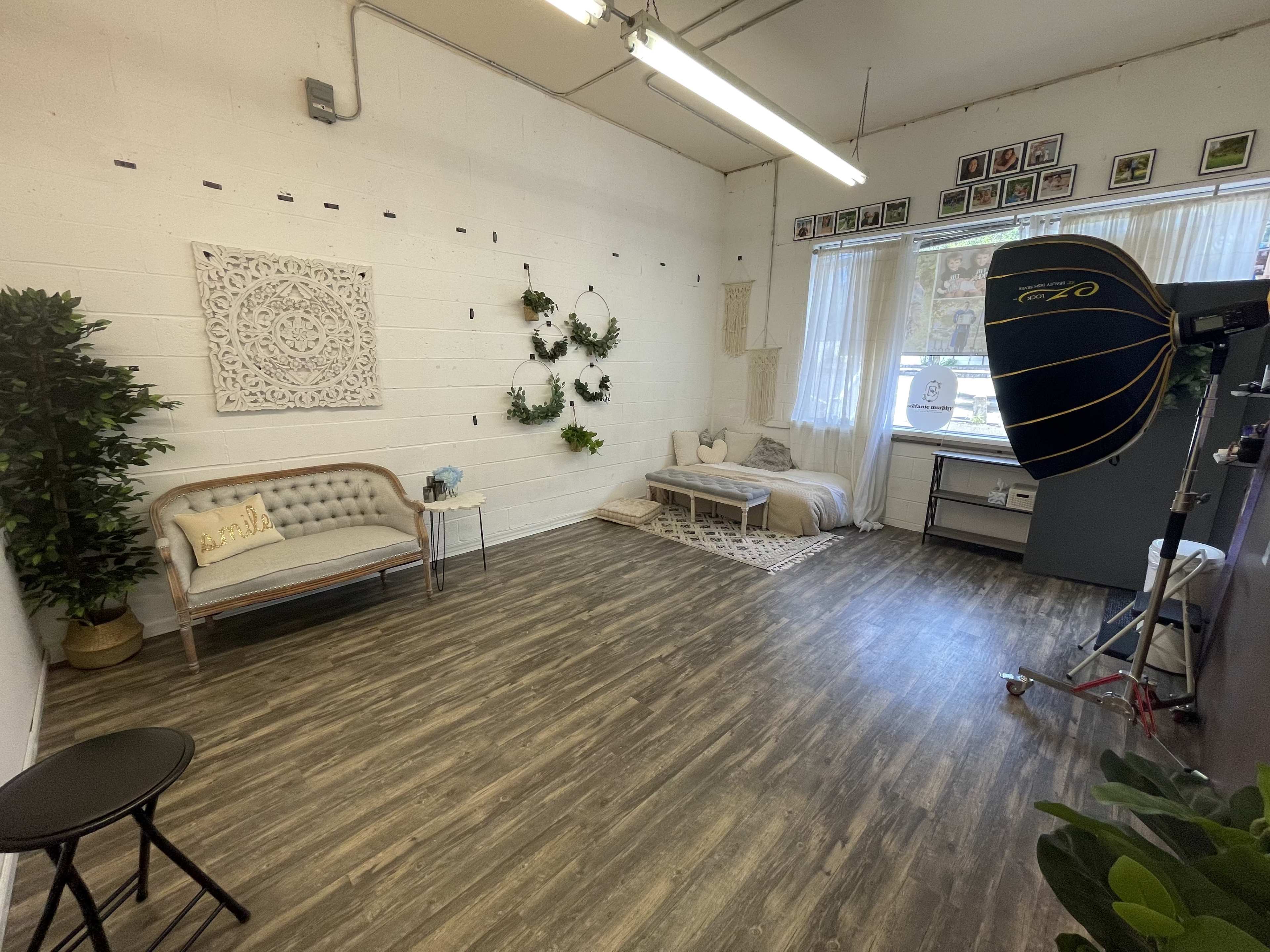 A spacious, well-lit room with a seating area, decorative wall elements, and a photography setup in the corner.