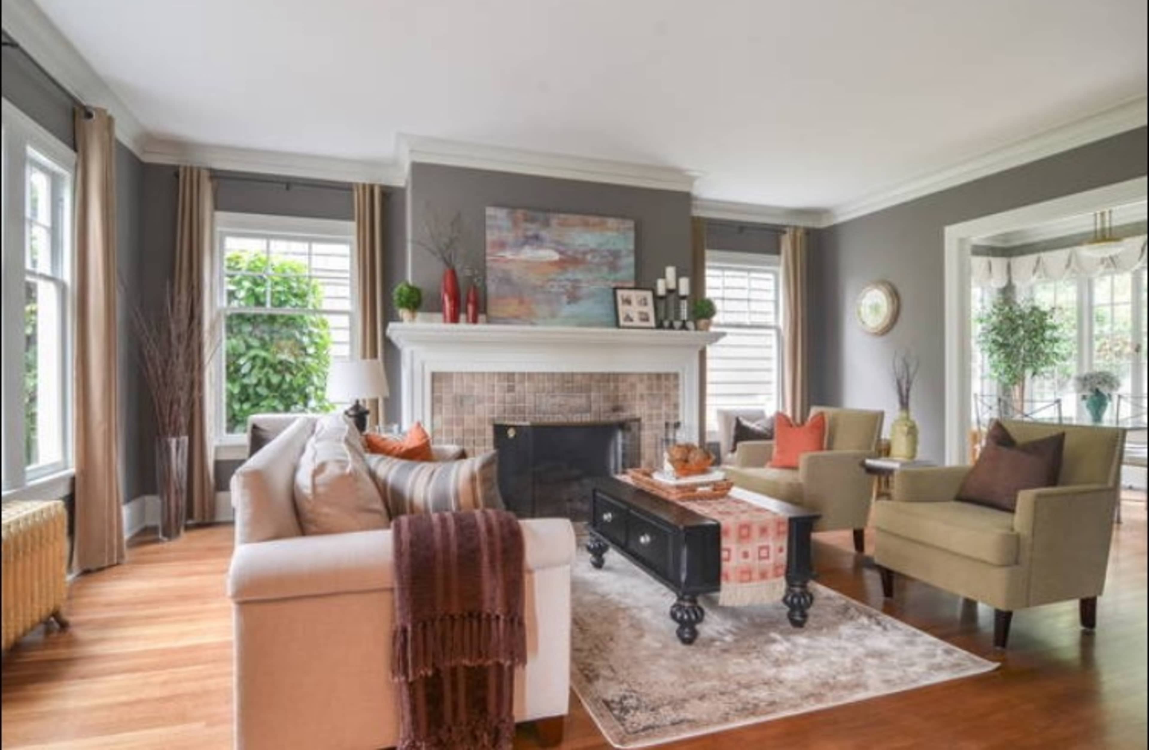 A modern living room features a fireplace, comfortable seating, and large windows allowing natural light.