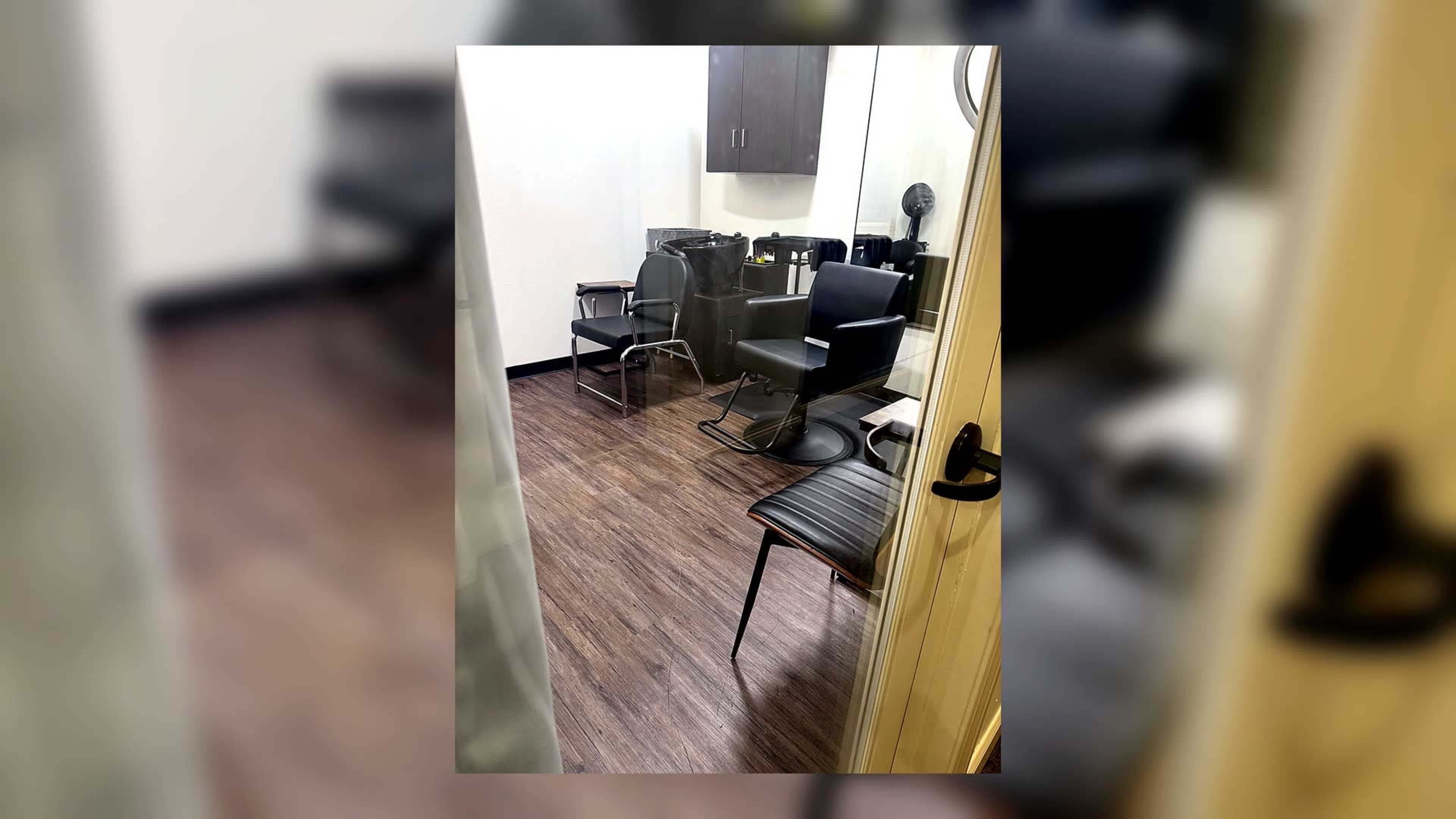 The image shows a small salon room with two styling chairs, a hair washing station, and a mirror on the wall.
