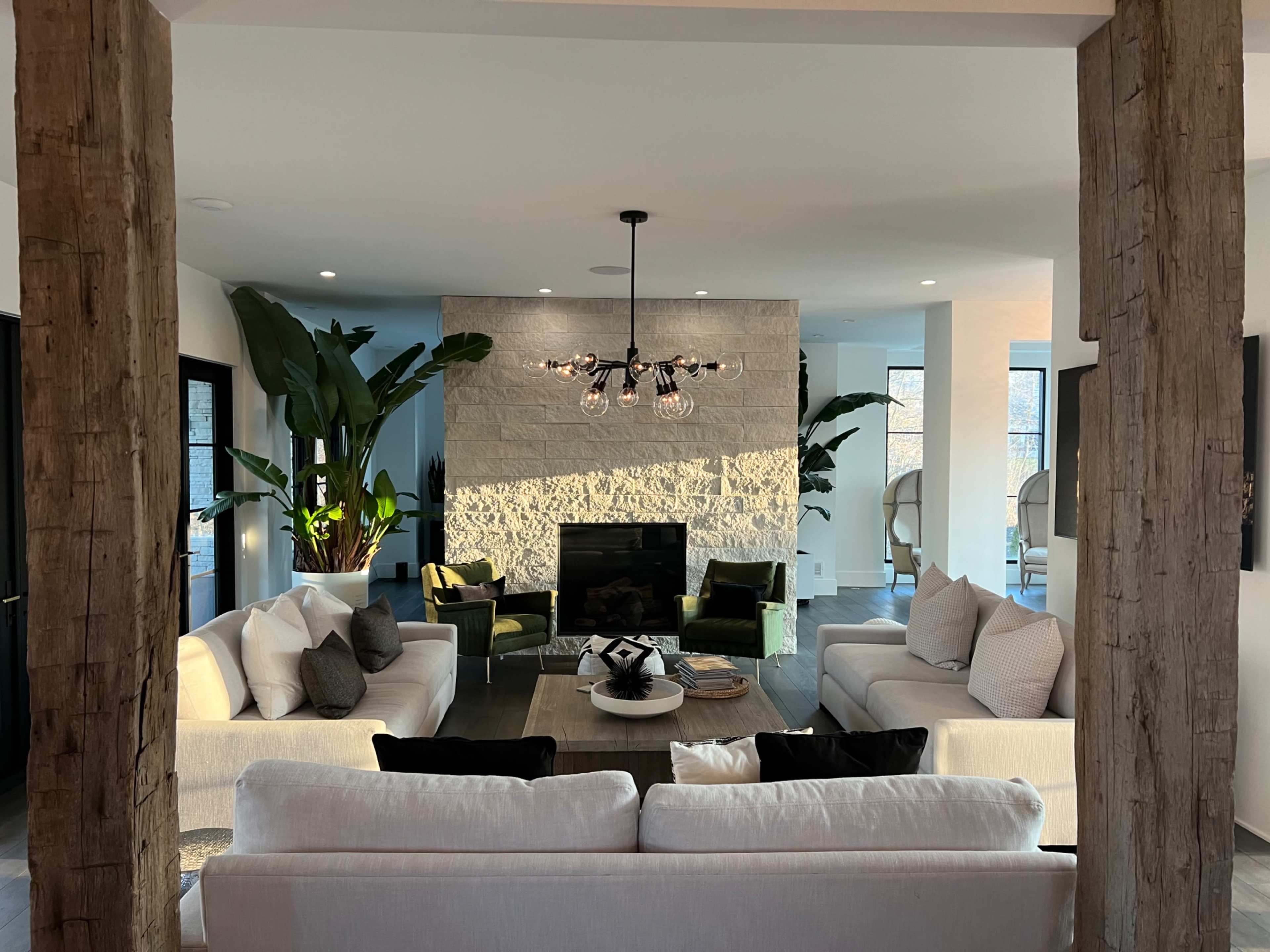 A modern living room features a stone accent wall, large windows, and two sofas arranged around a circular coffee table.