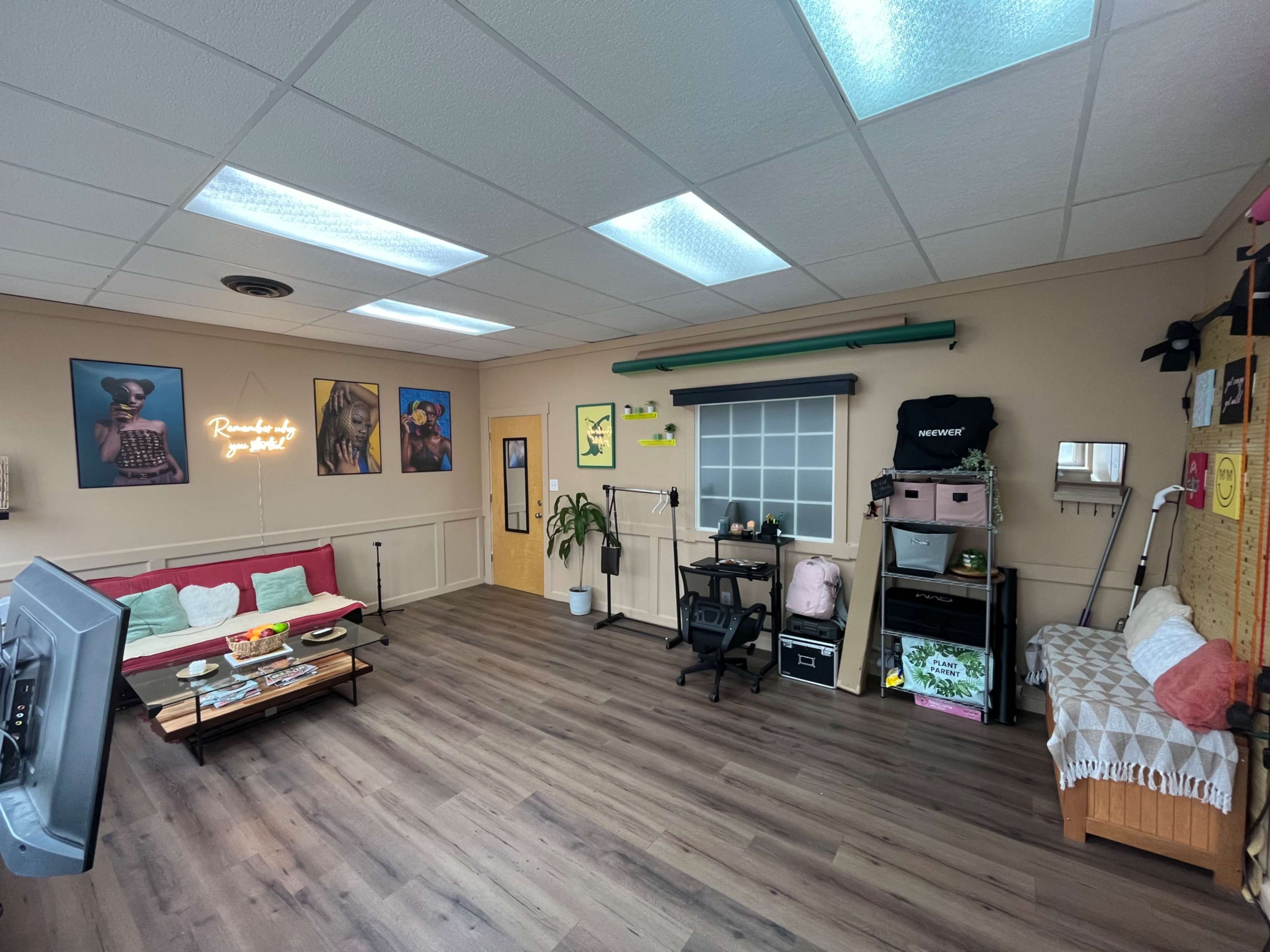 A well-organized office space with a sofa, wall art, a desk with a chair, and various decorative items.