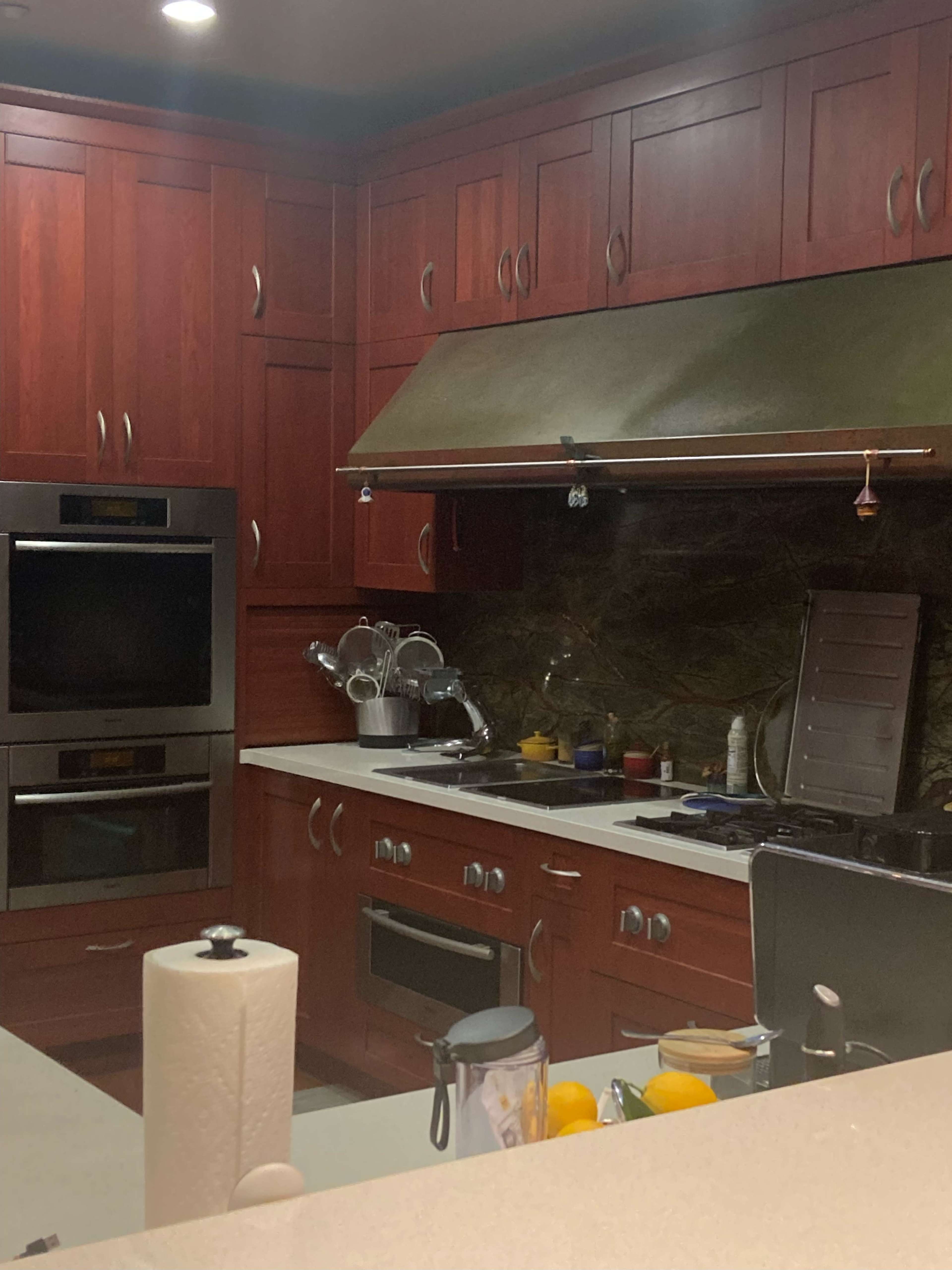 A modern kitchen with wooden cabinets, built-in appliances, and a countertop featuring various kitchen items.