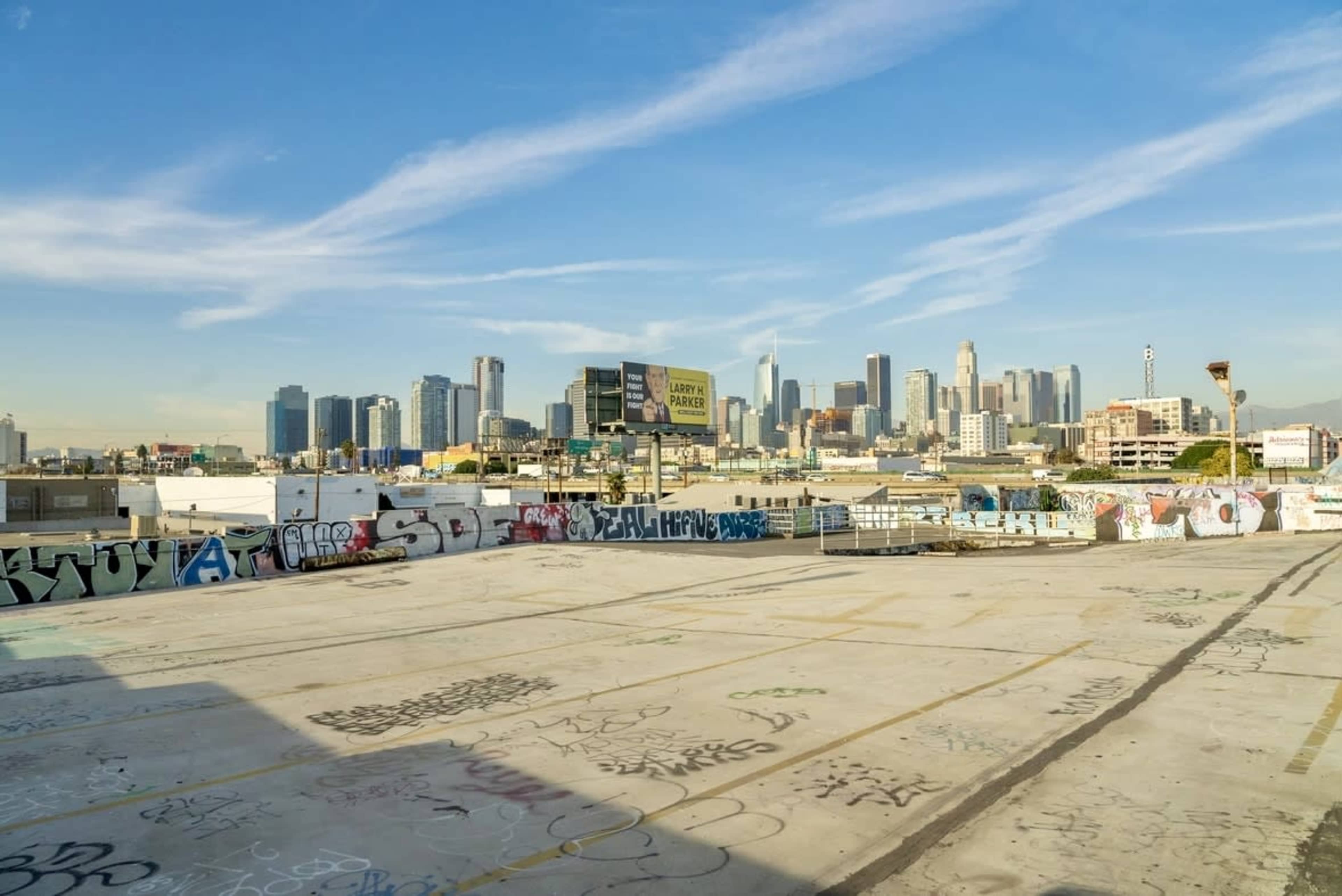The image shows a rooftop view of a city skyline with numerous buildings and graffiti-covered surfaces in the foreground.