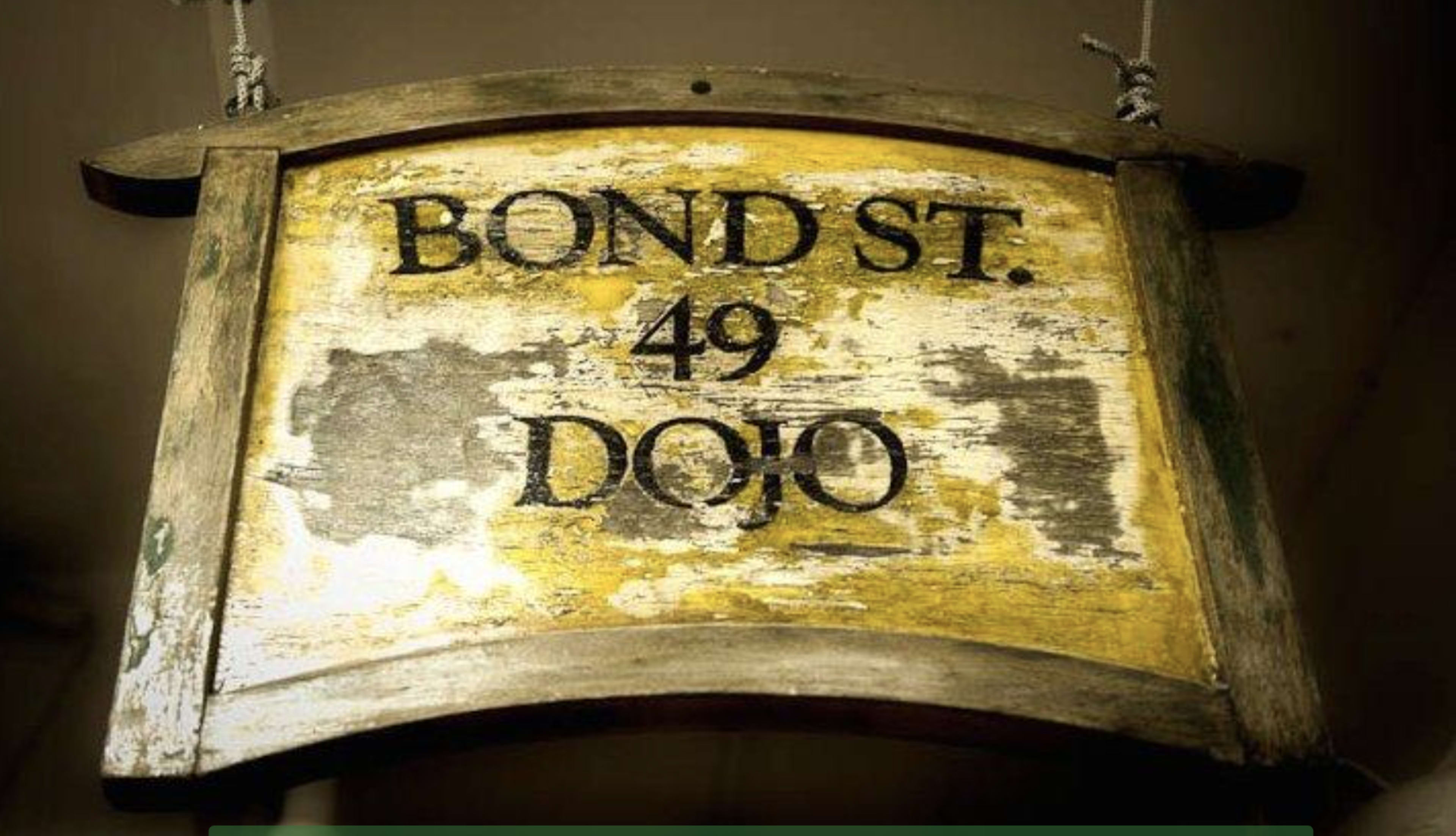 A weathered wooden sign displays the text "BOND ST. 49 DOJO."
